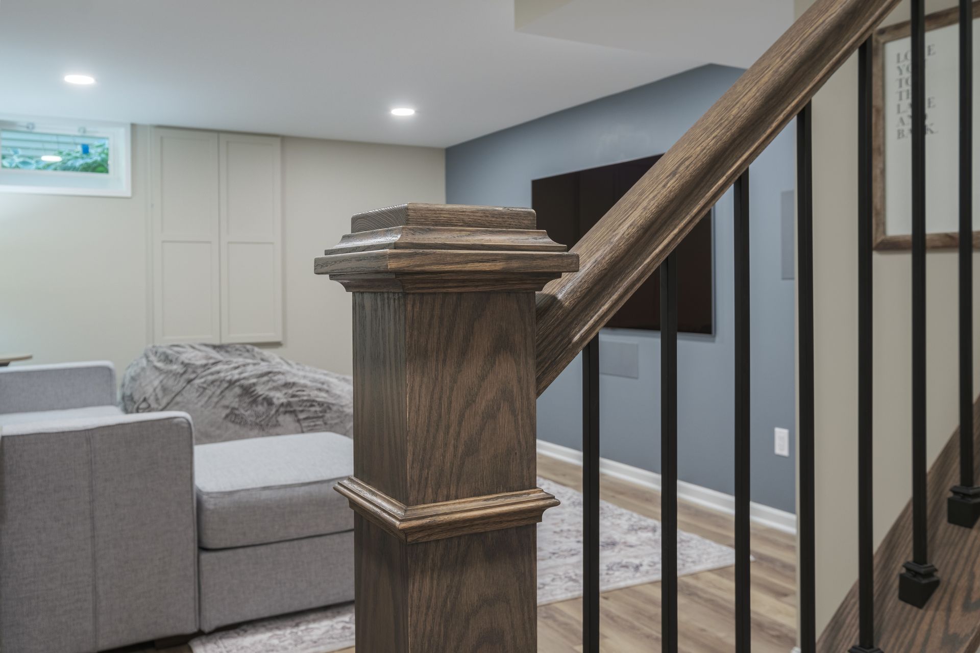 A staircase leading up to a living room with a couch and chairs.