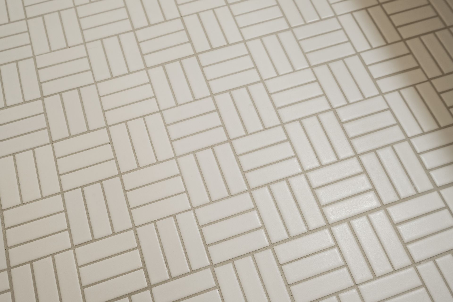 Off-white tile floor with a basketweave pattern and thin gray grout lines.