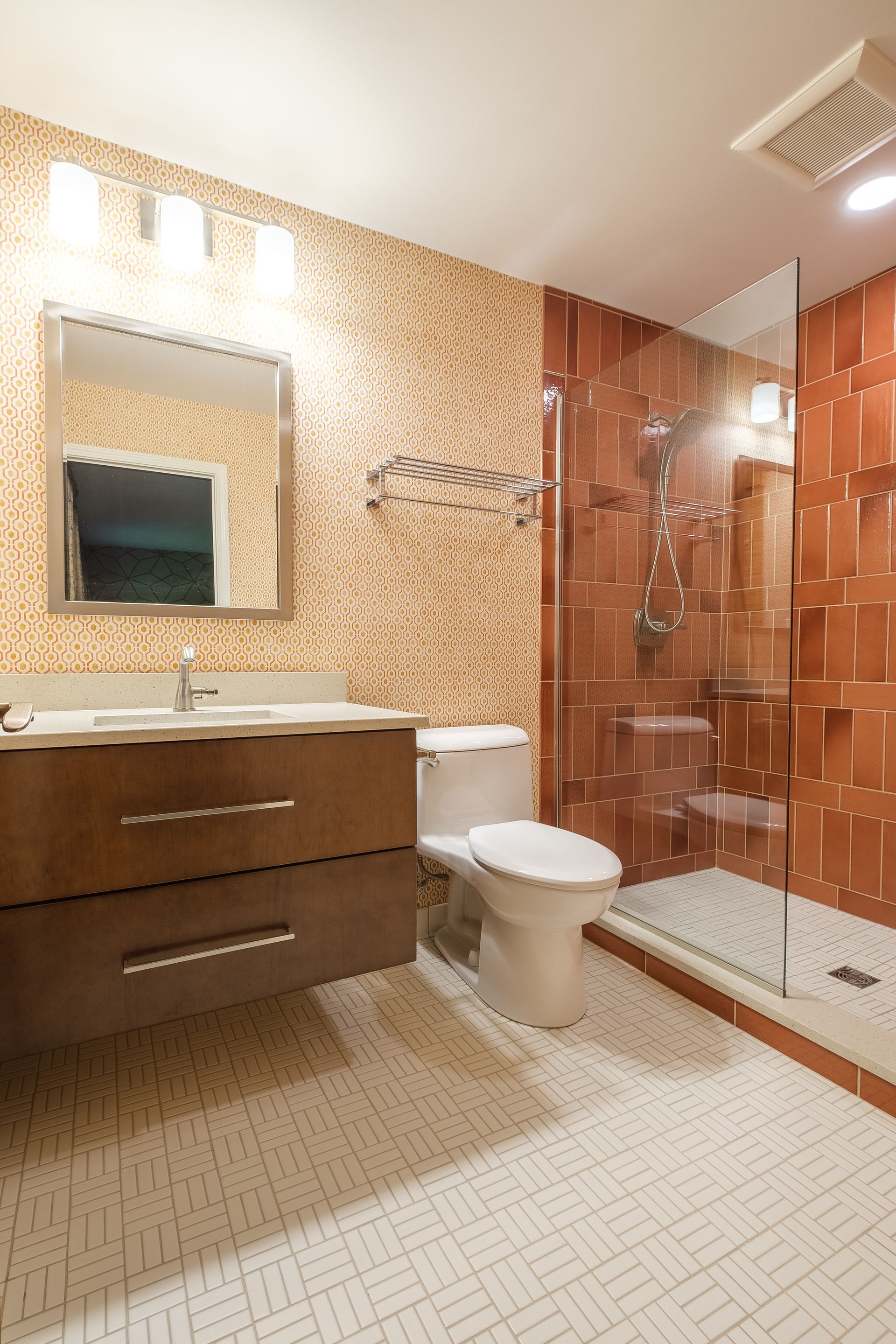 Bathroom with a dark wood vanity, white toilet, and orange and white tiled walls.