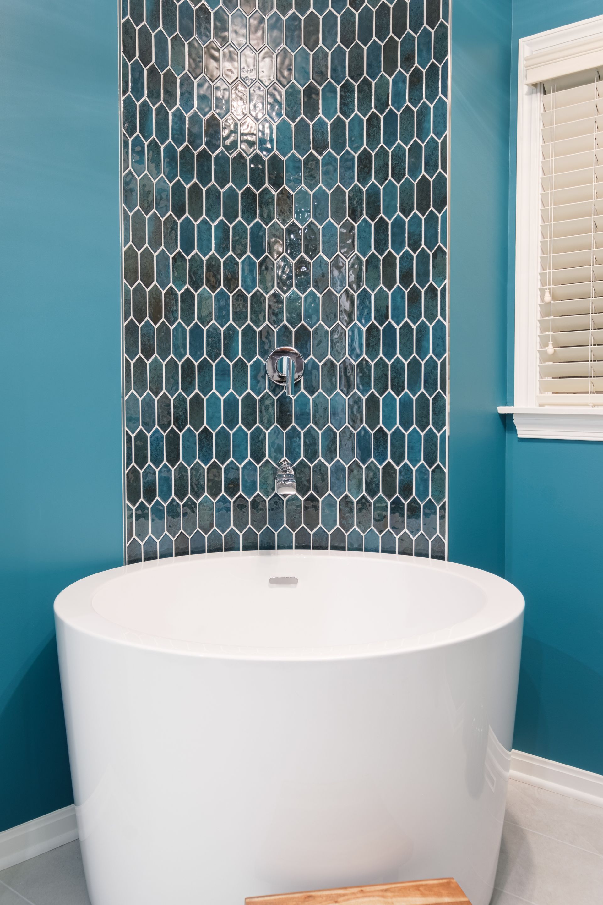 There is a bathtub in the bathroom with blue walls.