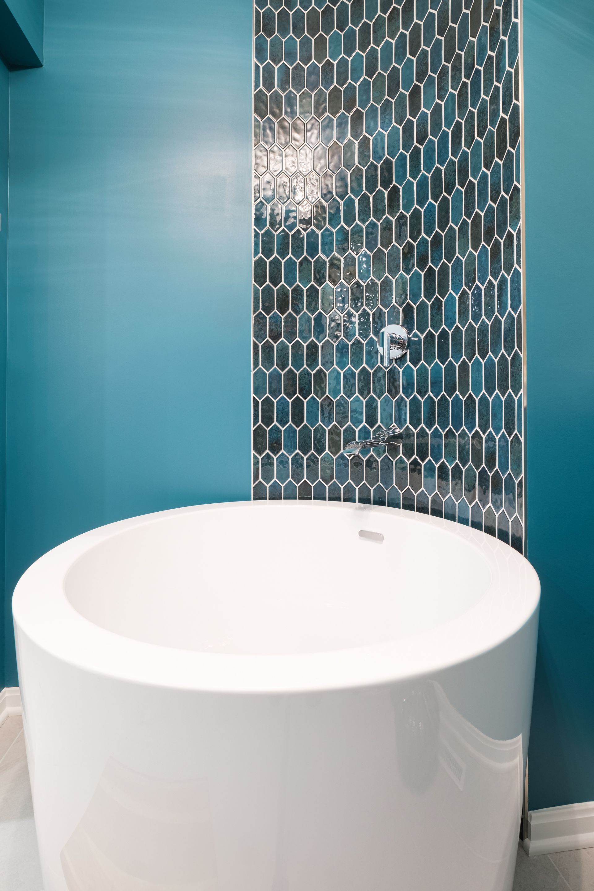 A white bathtub is sitting in a bathroom next to a blue wall.