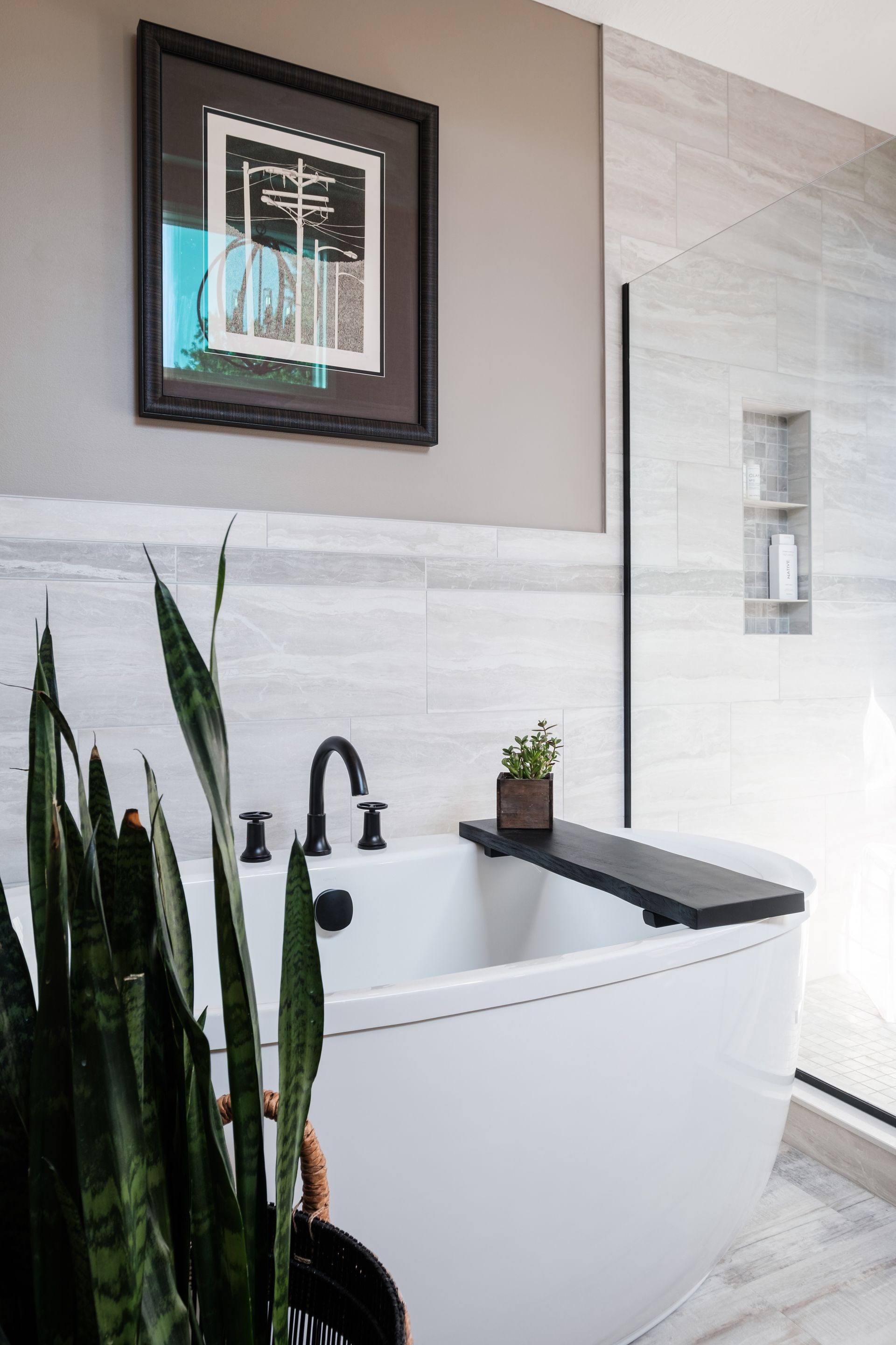 There is a picture on the wall above the bathtub in the bathroom.