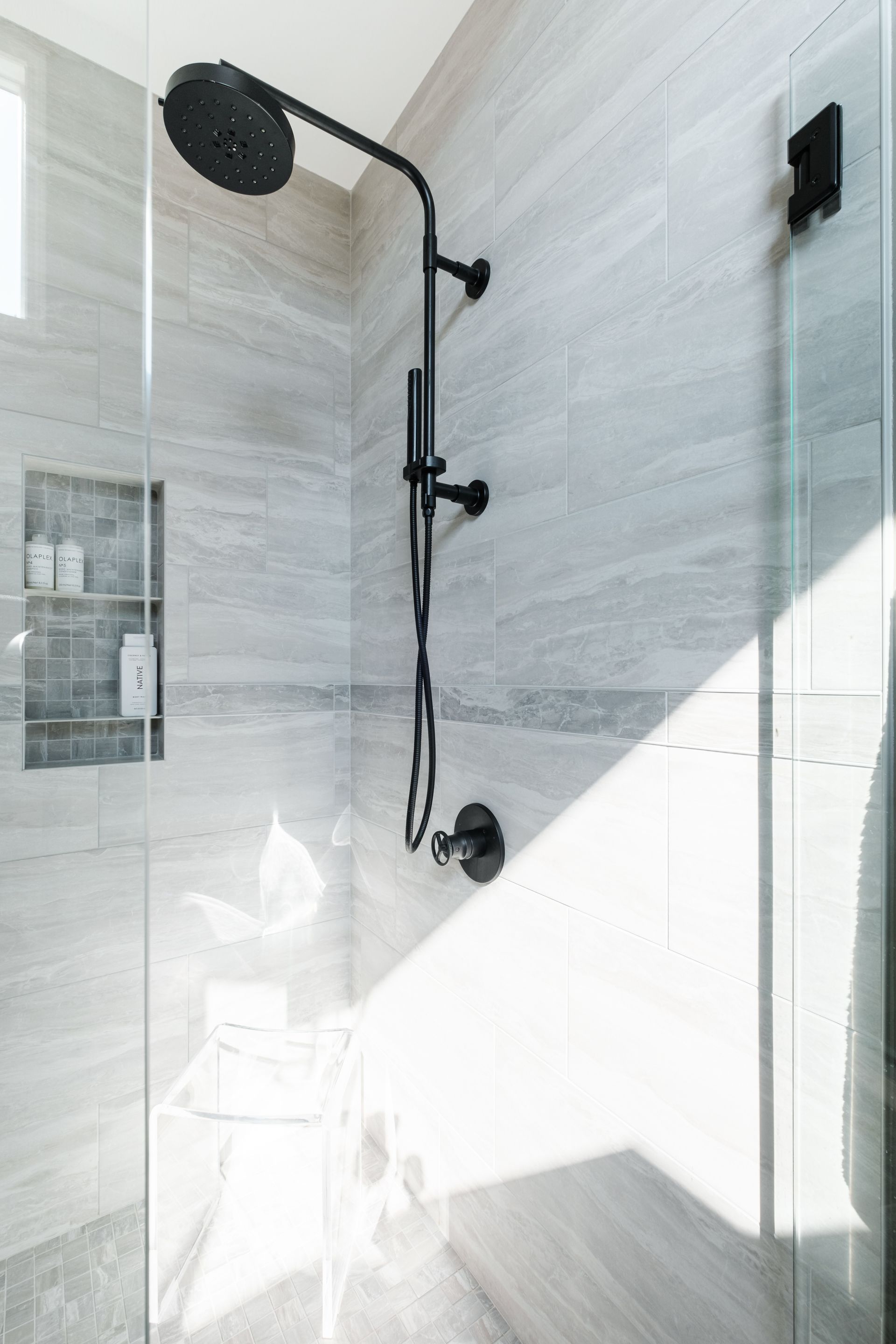 A shower with a black shower head and a glass door.