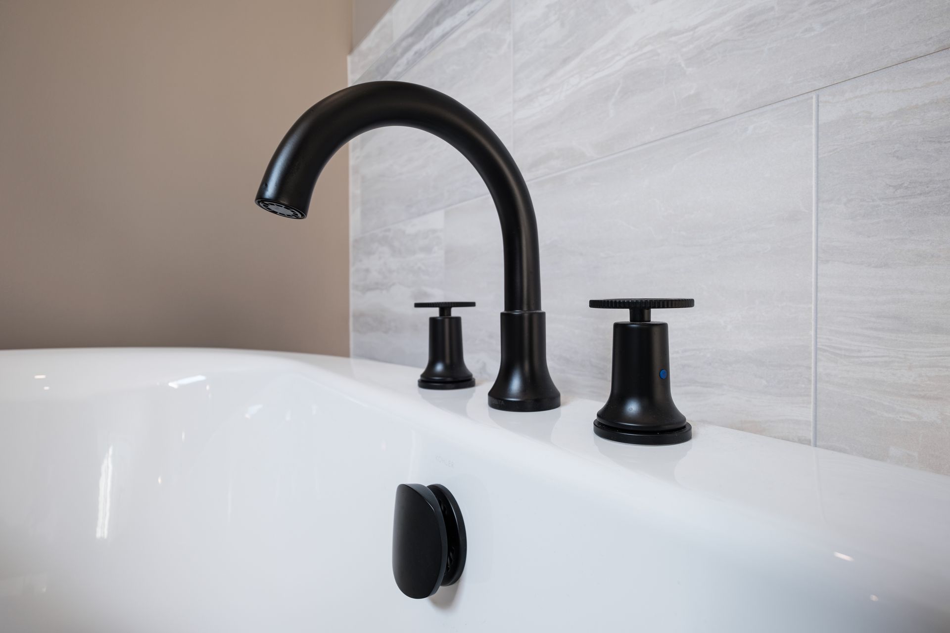 A black faucet is sitting on top of a white bathtub.