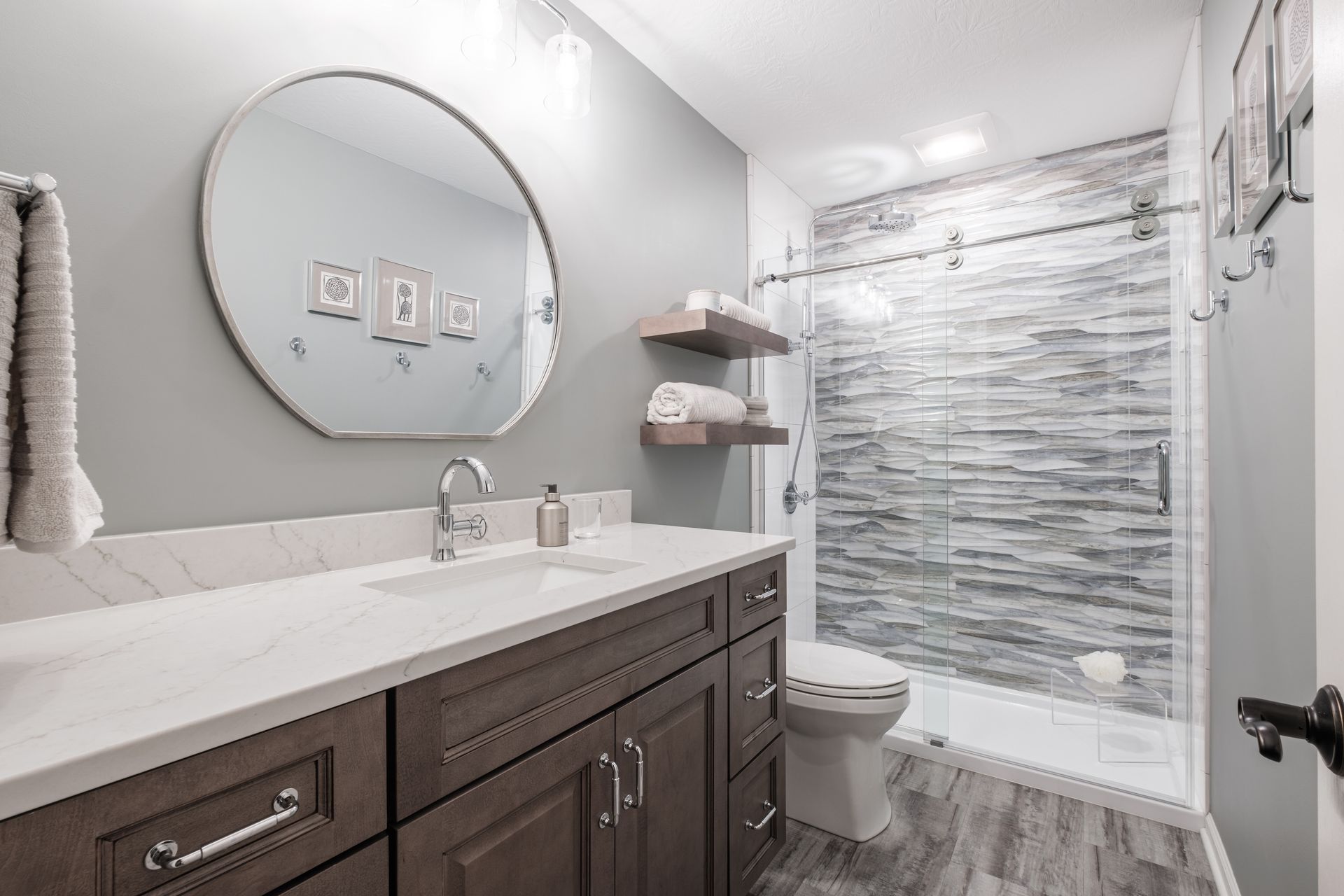 A bathroom with a sink , toilet , shower and mirror.