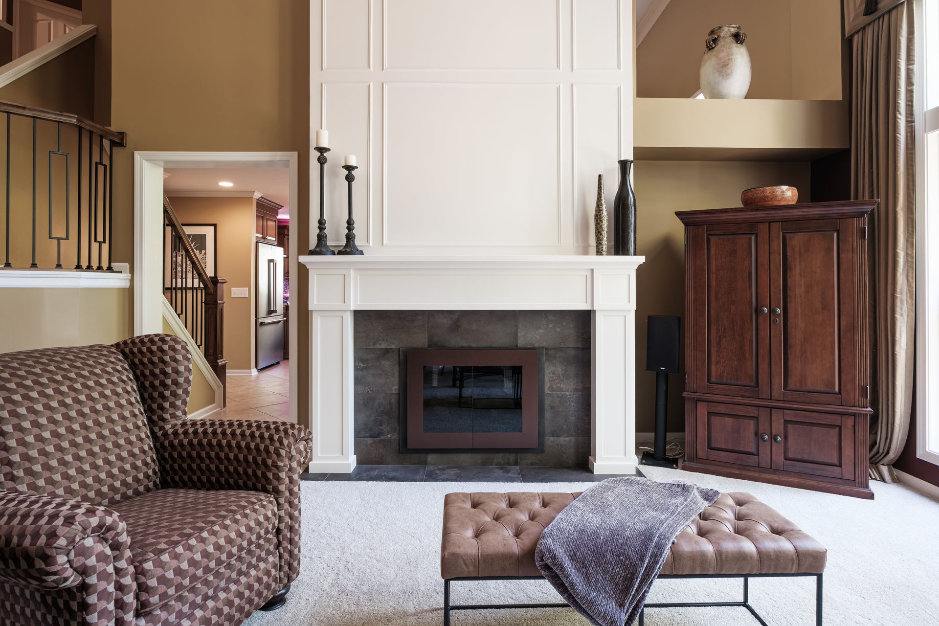 A living room with a fireplace , chair and ottoman.