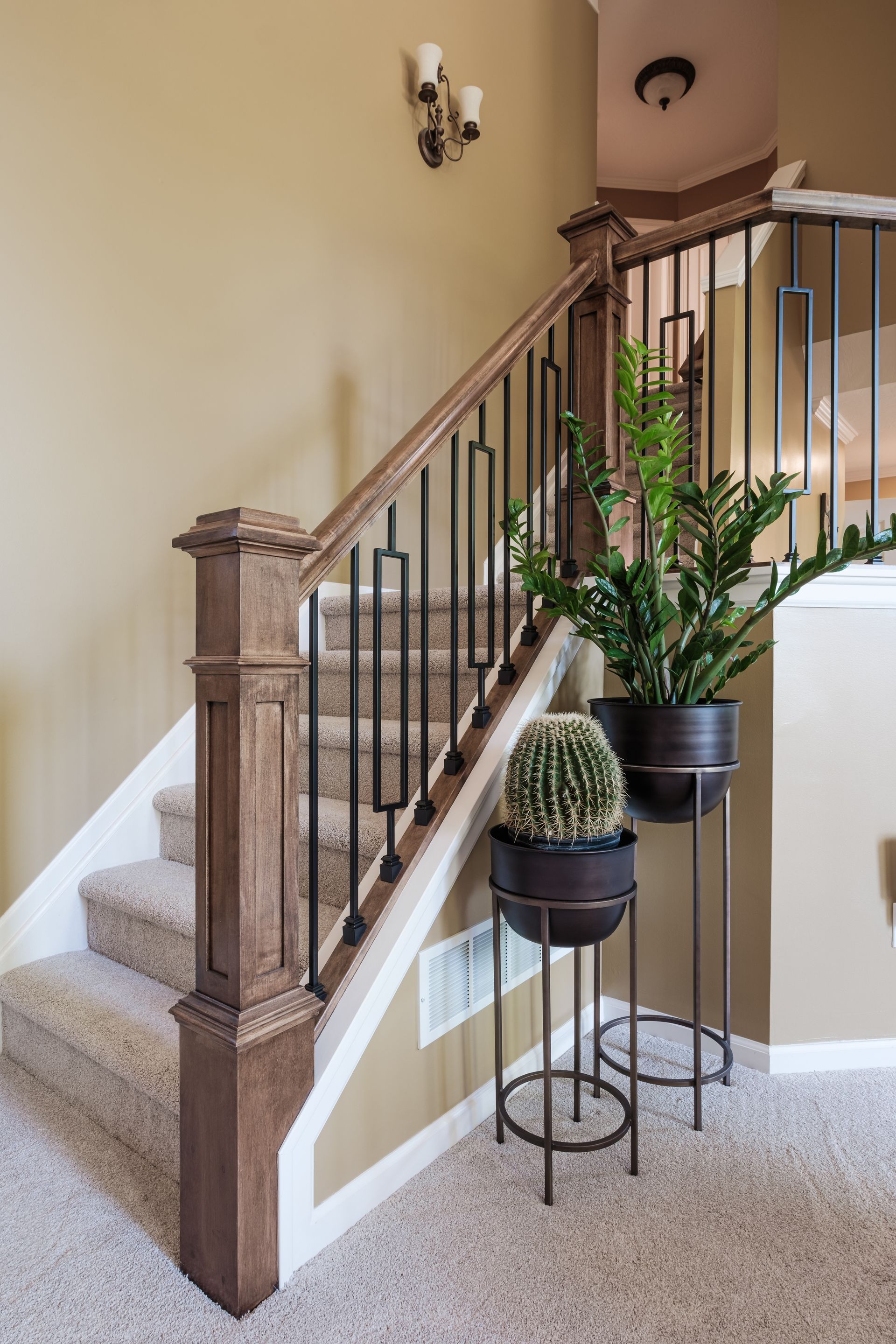 A staircase with a wooden railing and potted plants on the steps.