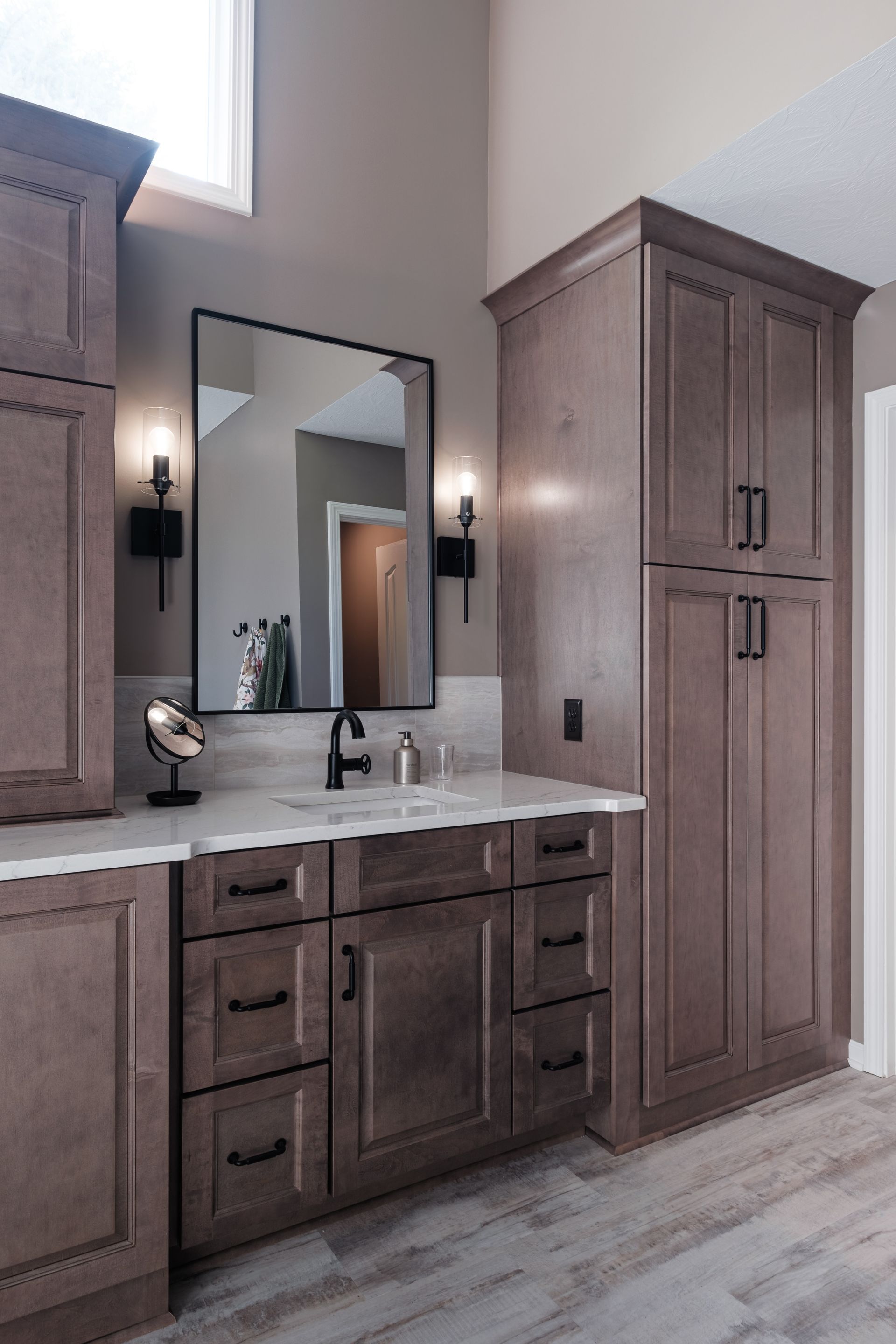 A bathroom with a sink , mirror , cabinets and drawers.