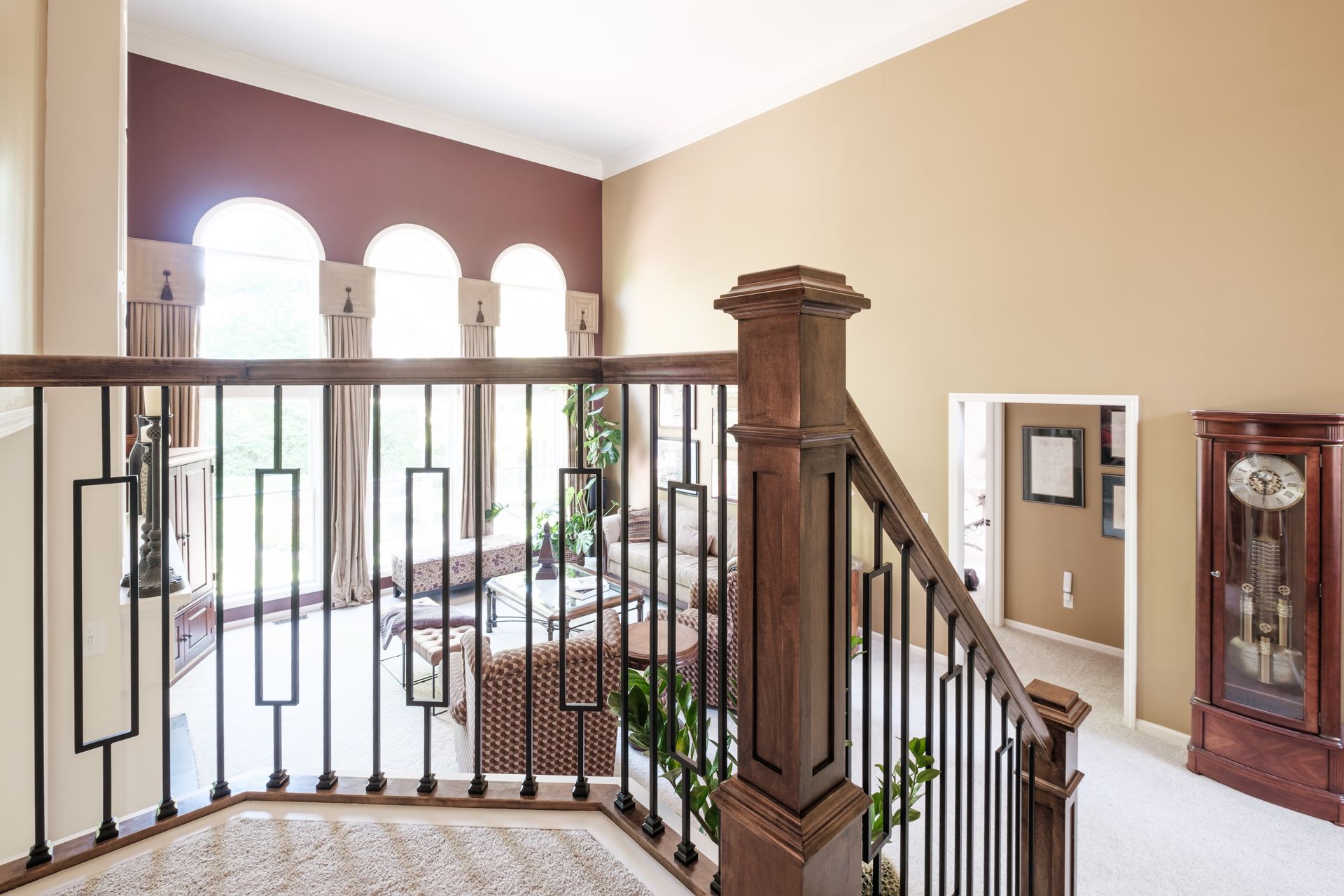 A staircase in a house with a wrought iron railing and a clock.