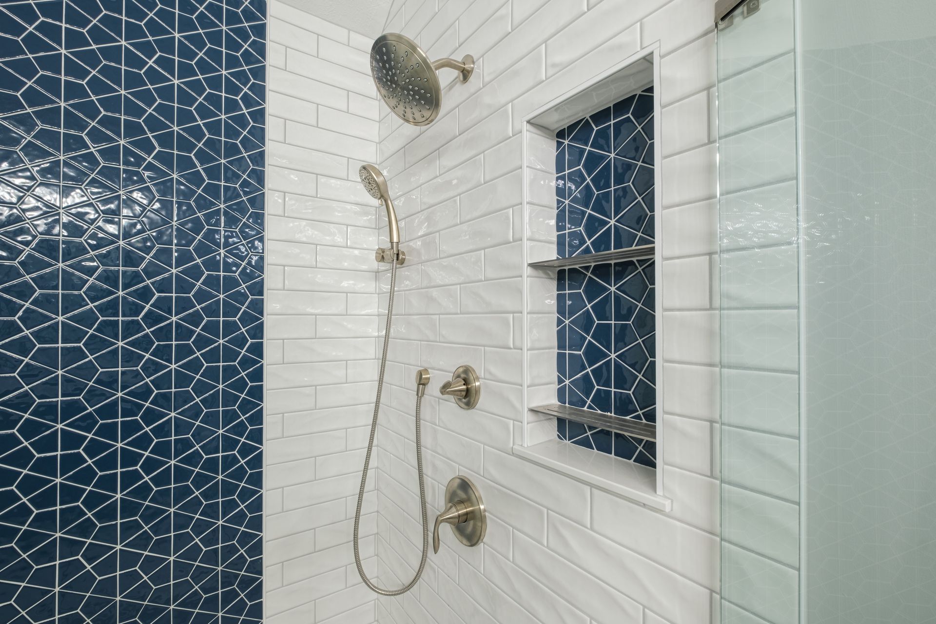 A shower with blue and white tiles and a shower head.