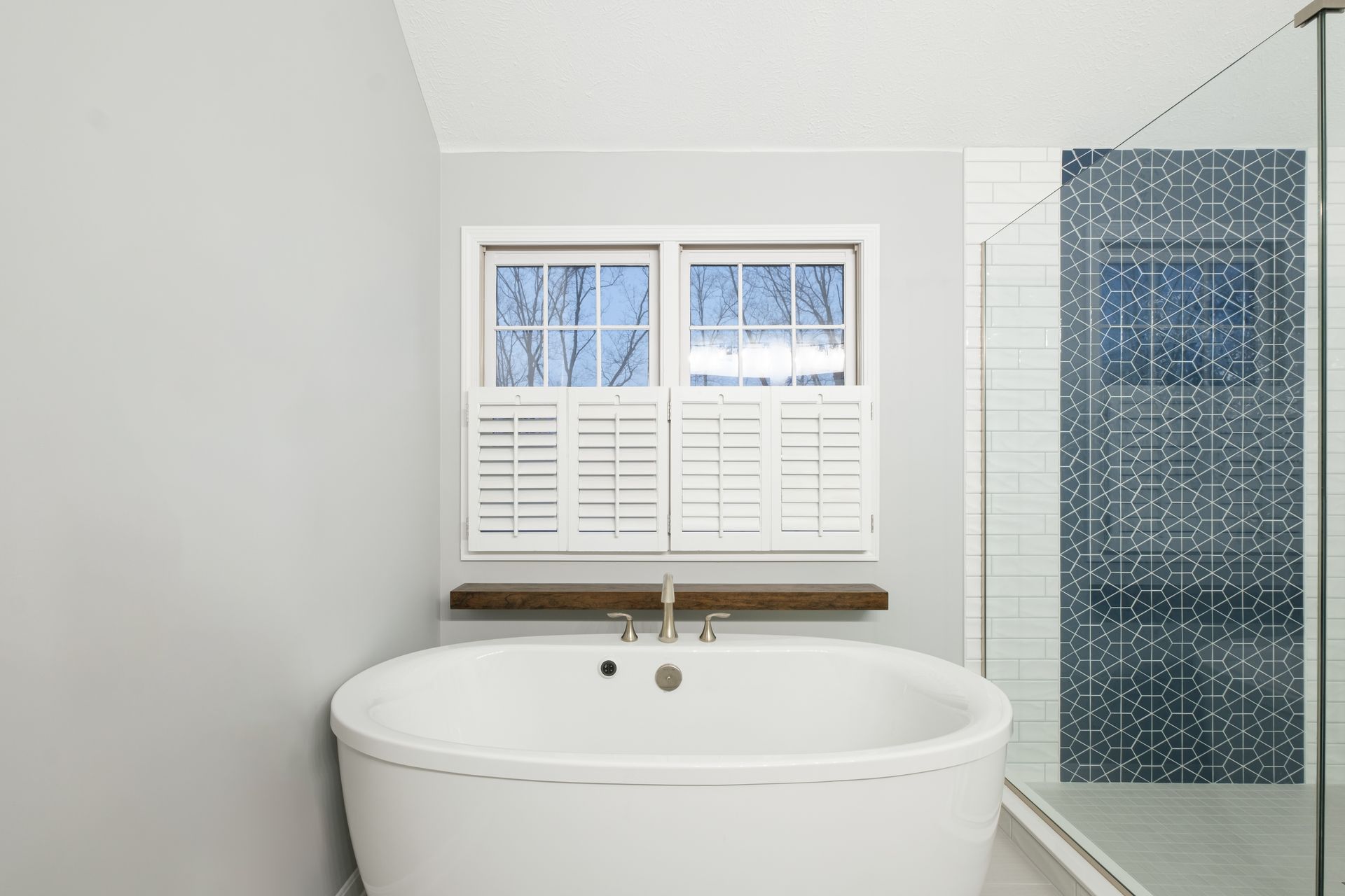 A bathroom with a tub , shower and two windows.