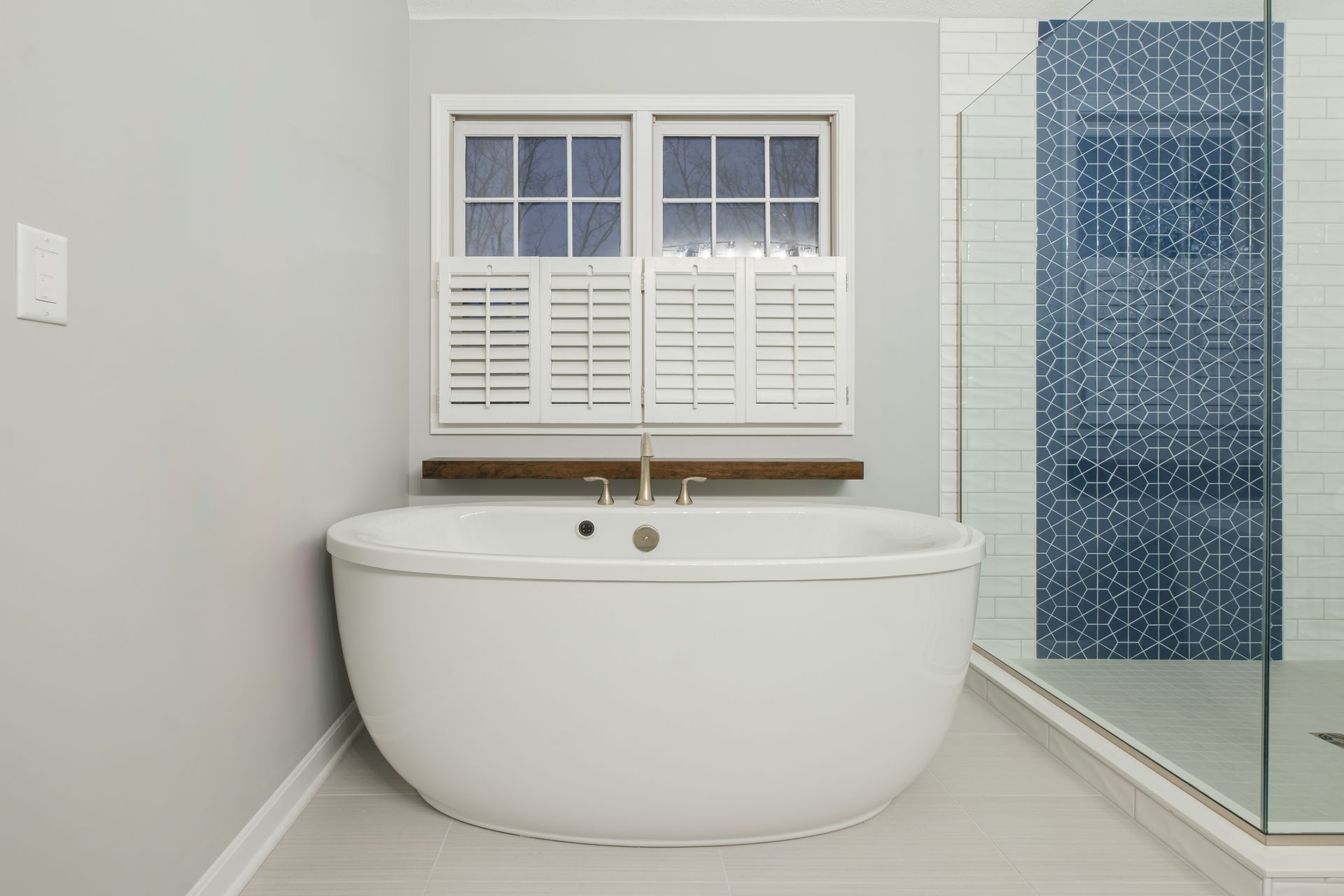 A bathroom with a bathtub , shower , and window.