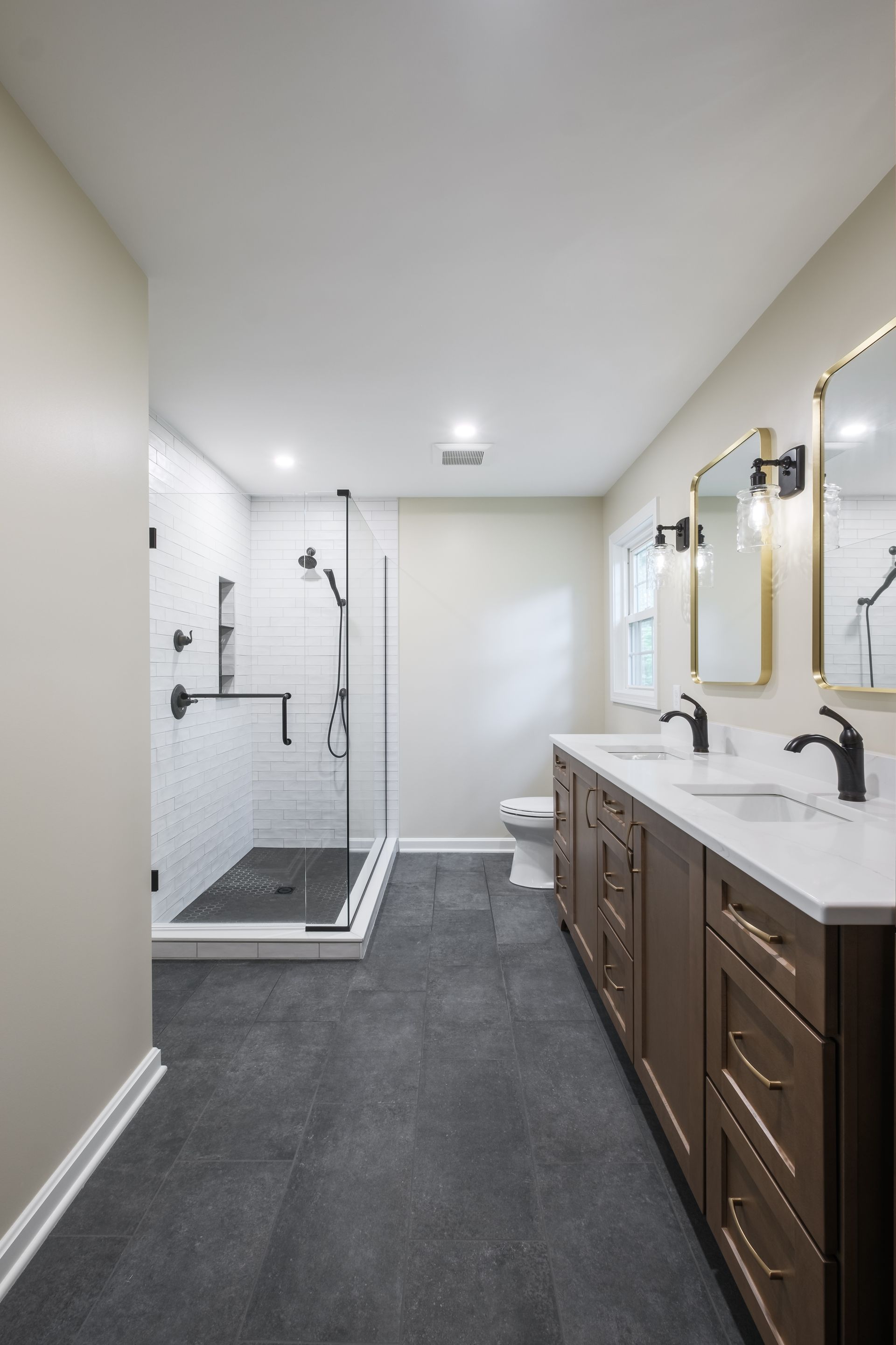 A bathroom with two sinks , a toilet , and a walk in shower.
