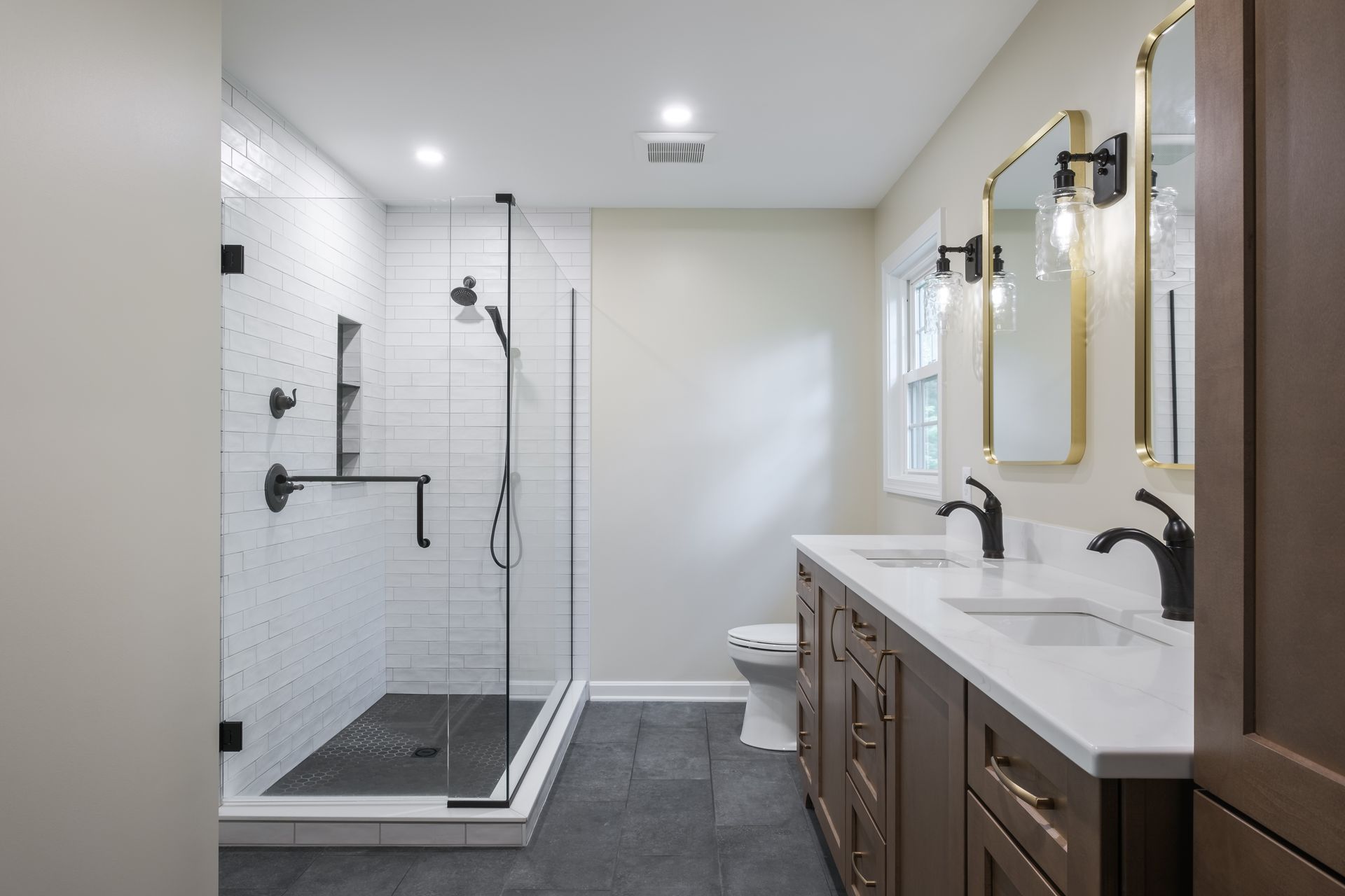 A bathroom with two sinks , a toilet , and a walk in shower.