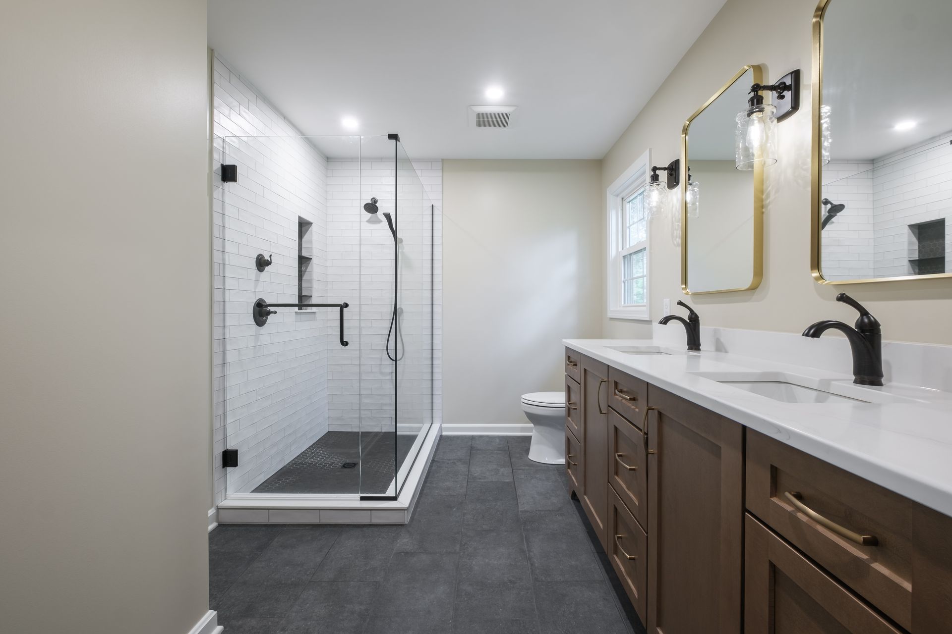 A bathroom with two sinks , a toilet , and a walk in shower.