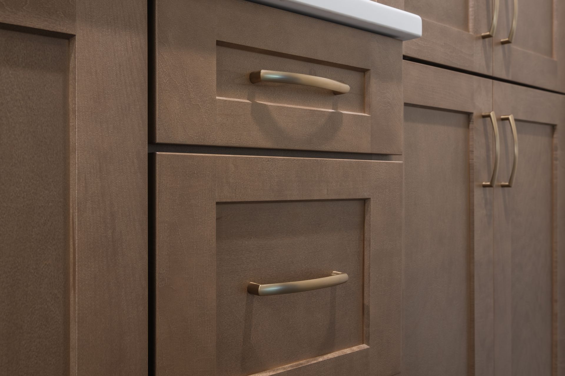 A kitchen with wooden cabinets and drawers with brass handles