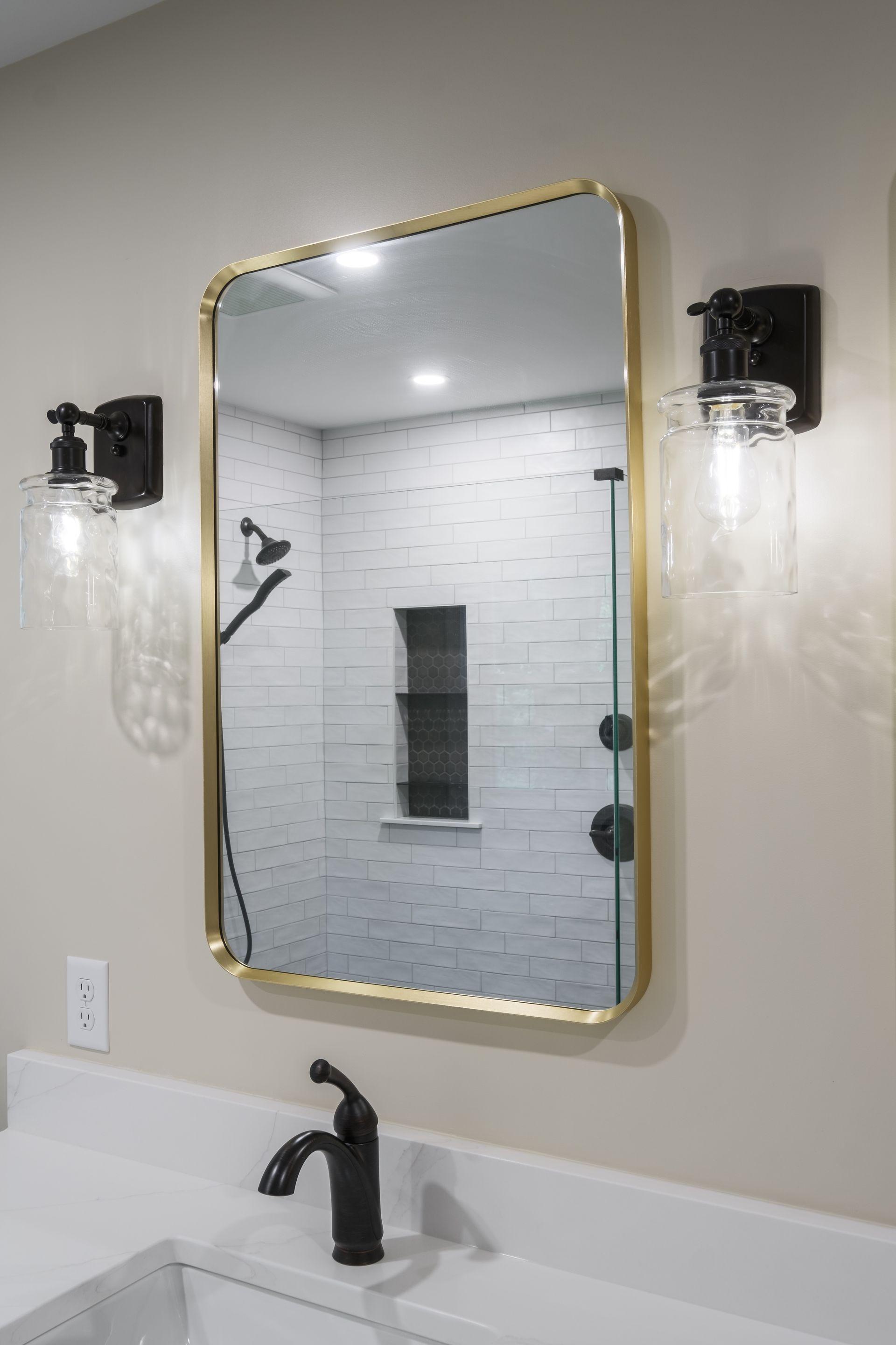 A bathroom with a large mirror hanging on the wall above a sink.
