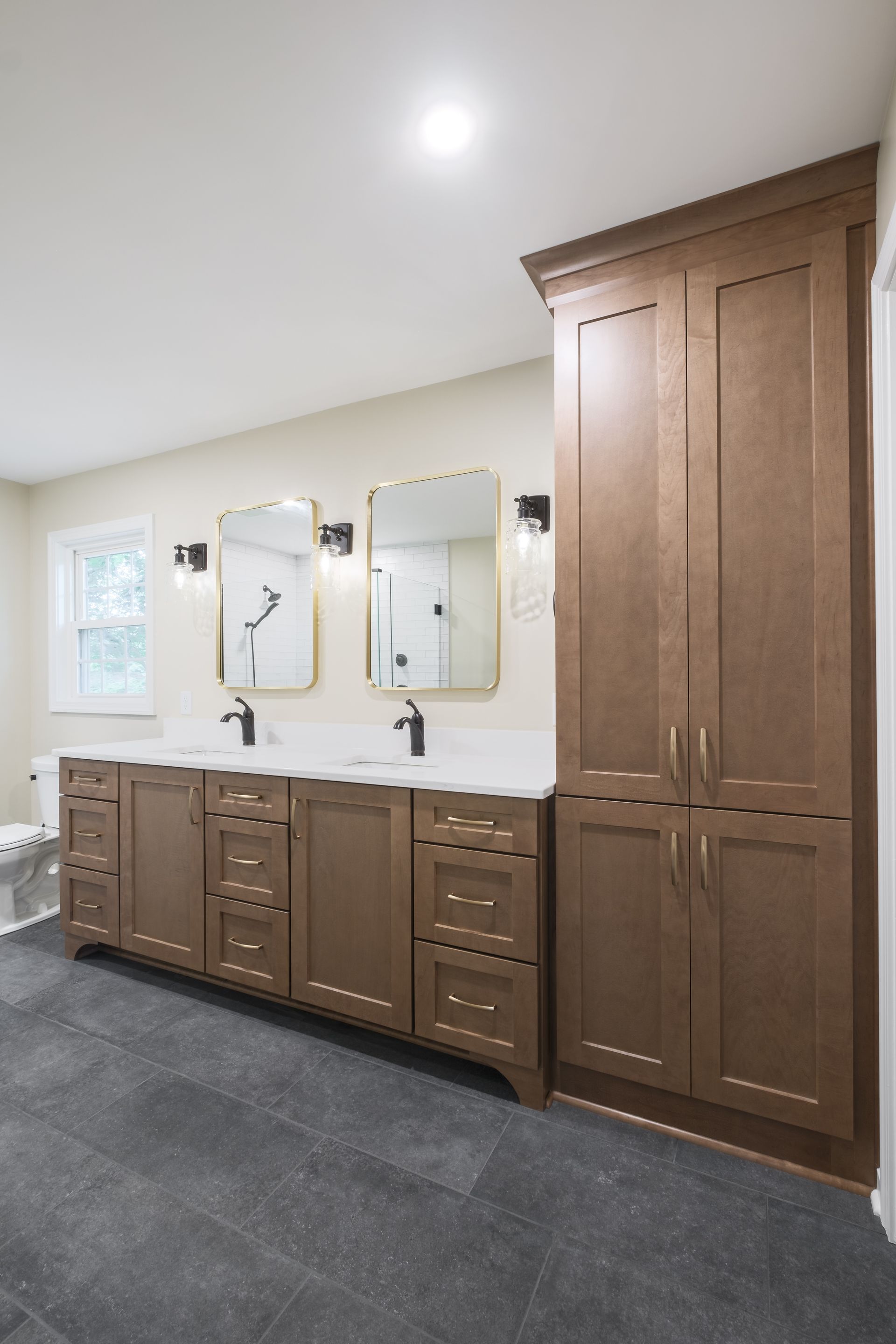 A bathroom with two sinks , two mirrors and a toilet.