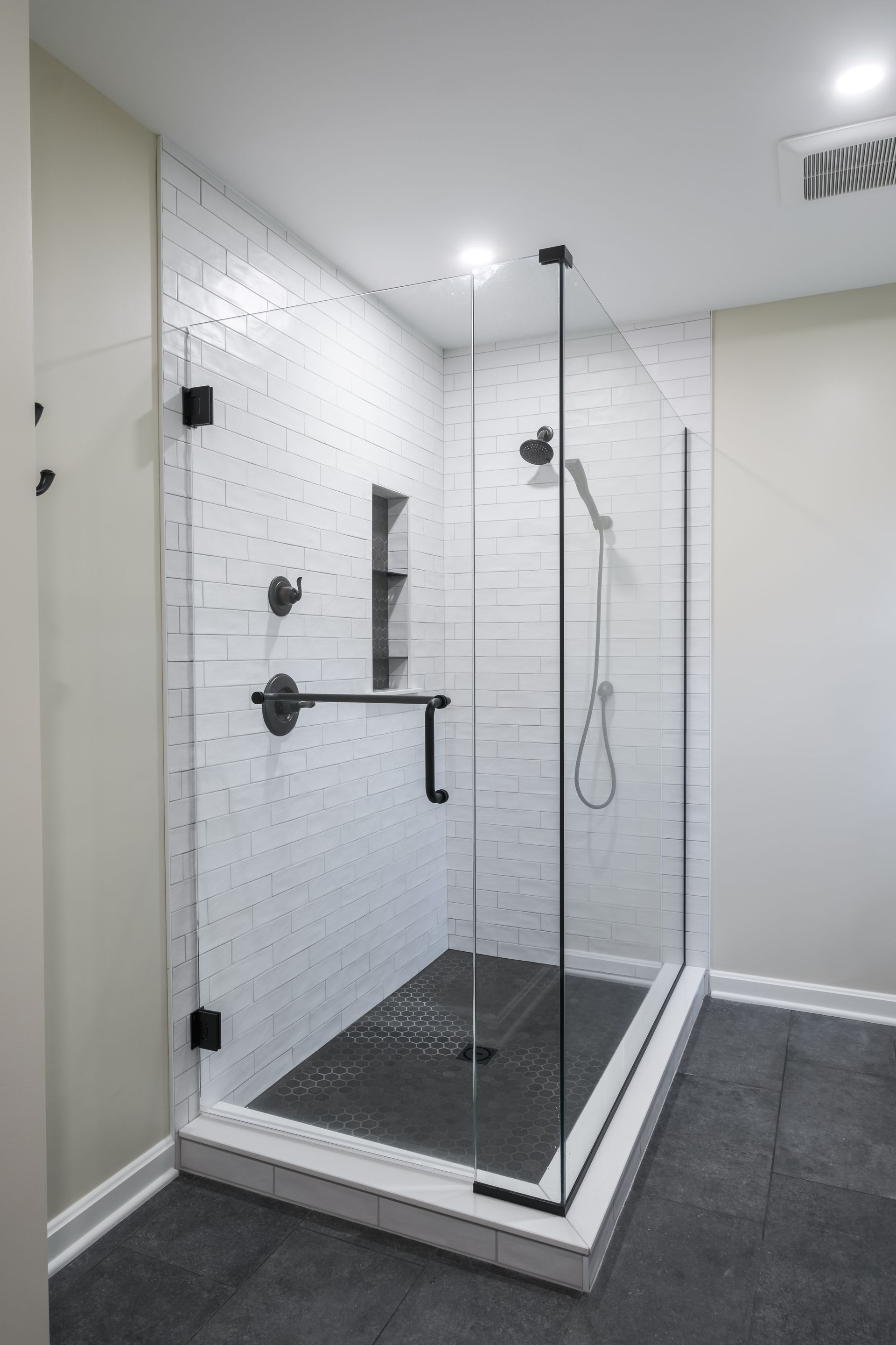 A bathroom with a walk in shower with a glass door.