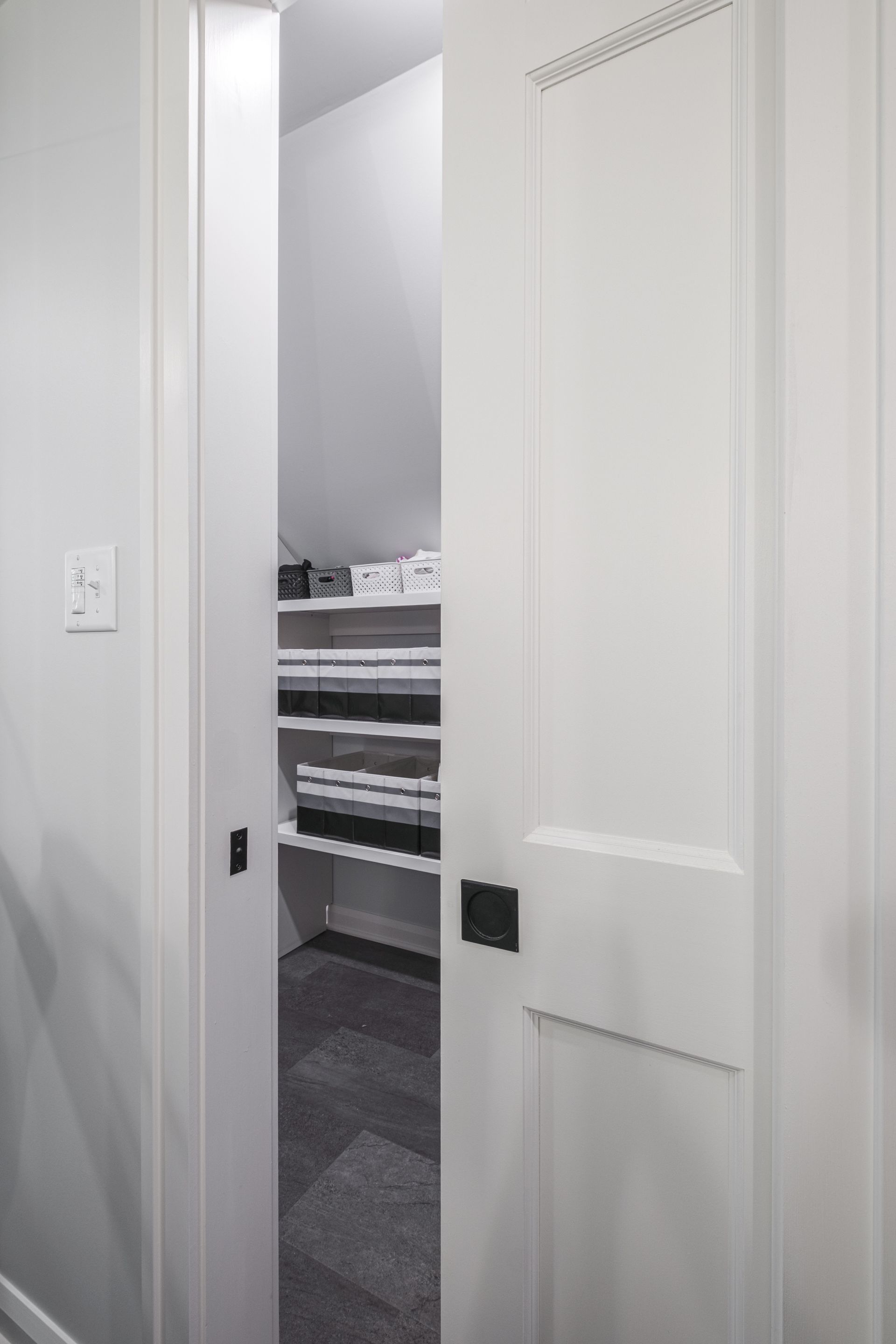 White pocket door partially open to reveal shelves inside a closet.