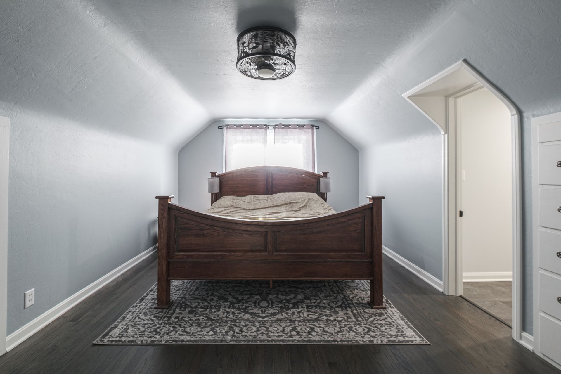 Bedroom with a bed, rug, and doorway under a sloped ceiling.