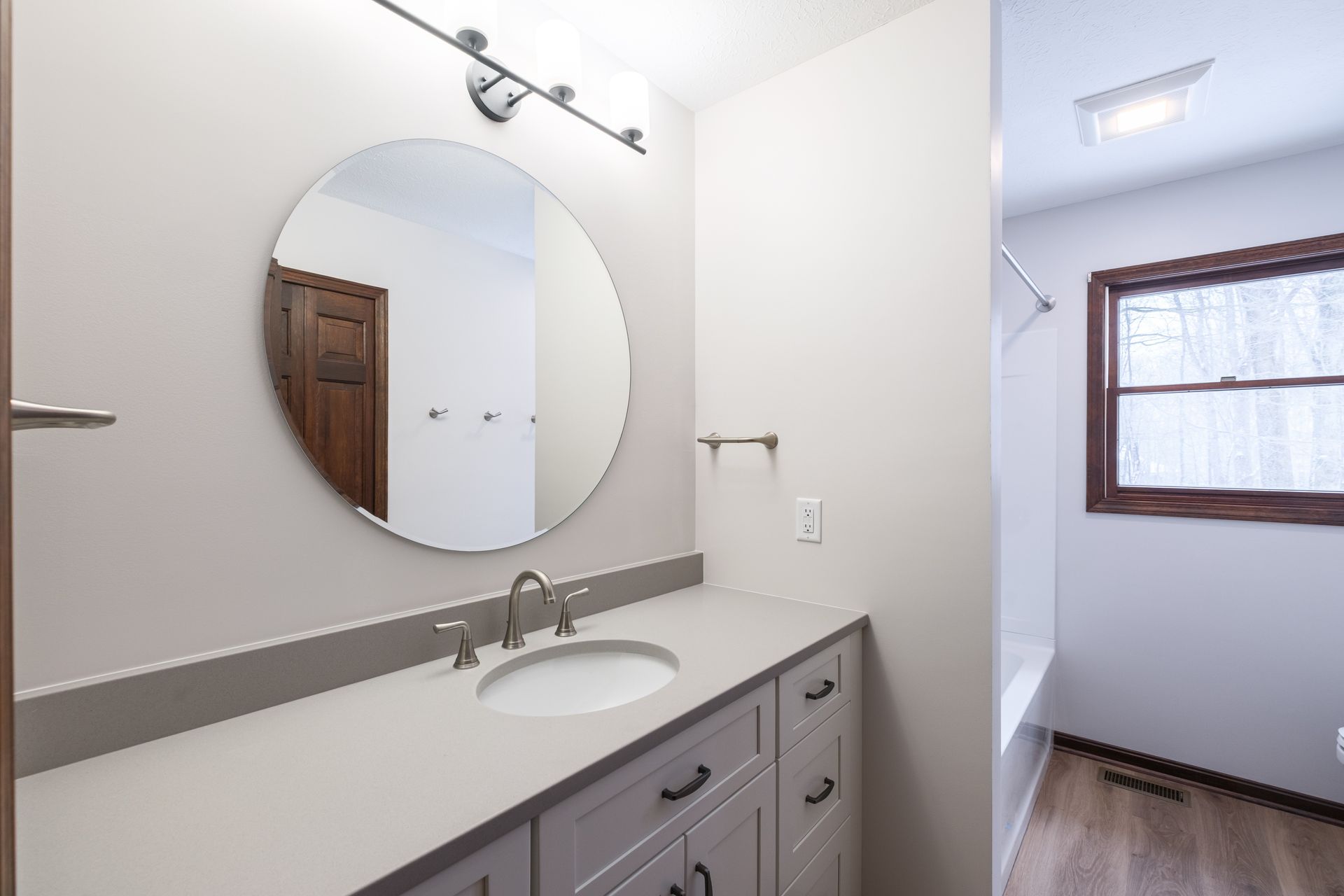 Bathroom with marble shower, long vanity, and gray flooring.