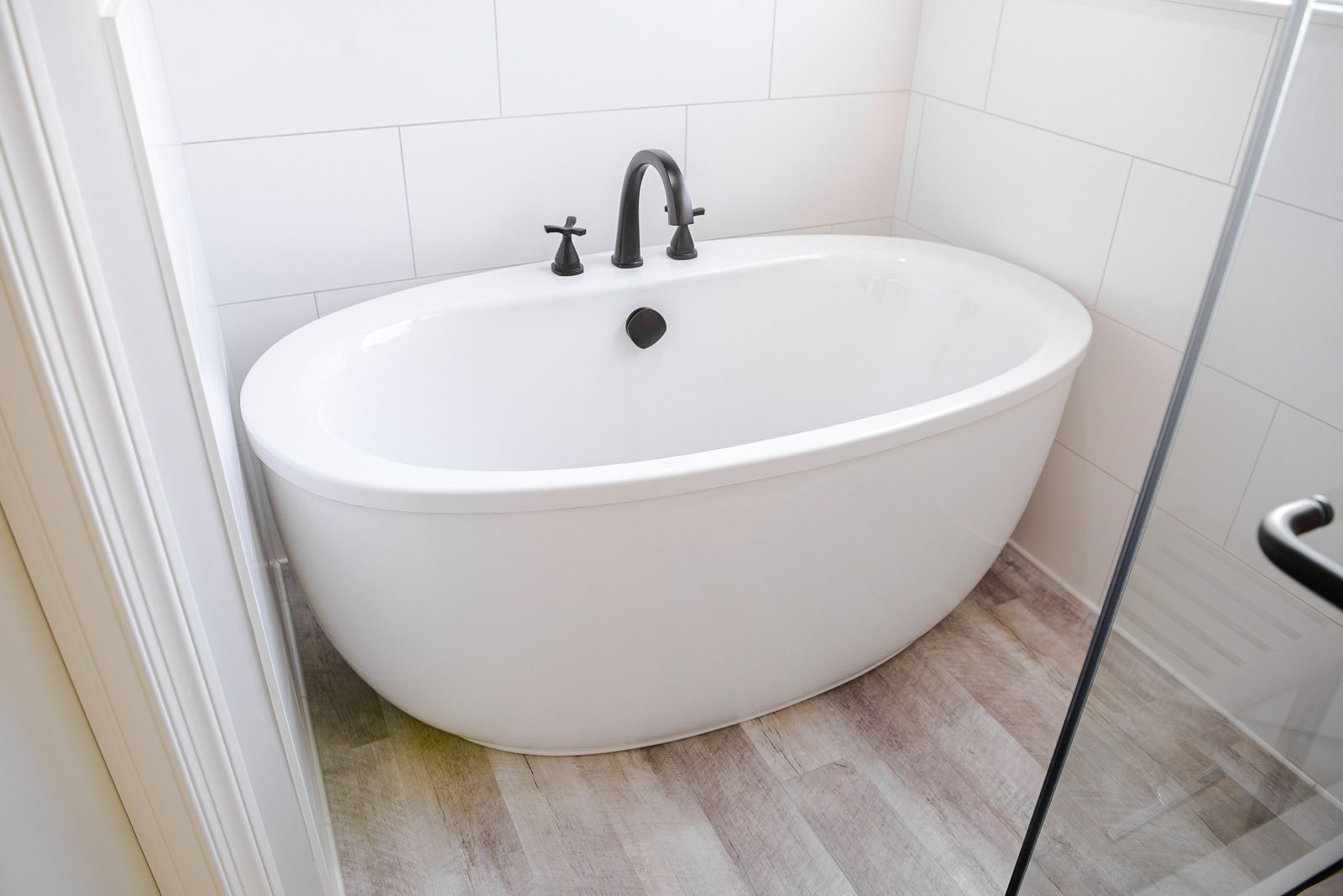 A white bathtub is sitting in a bathroom next to a glass shower door.