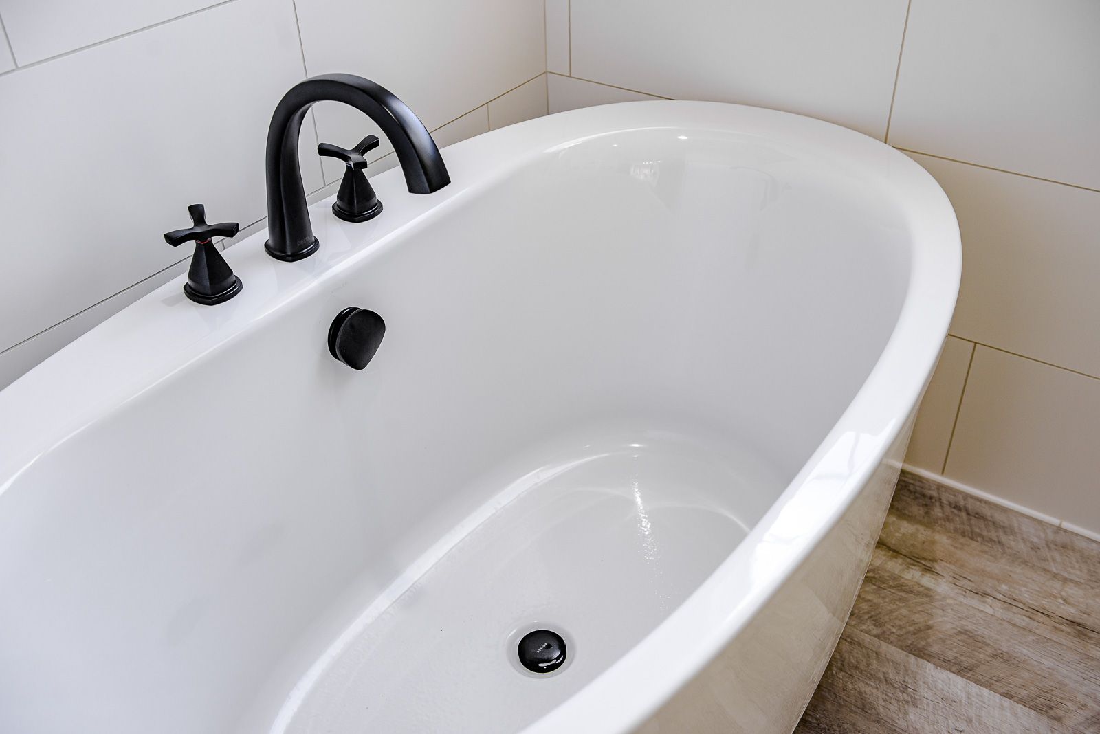 A white bathtub with black faucets in a bathroom.