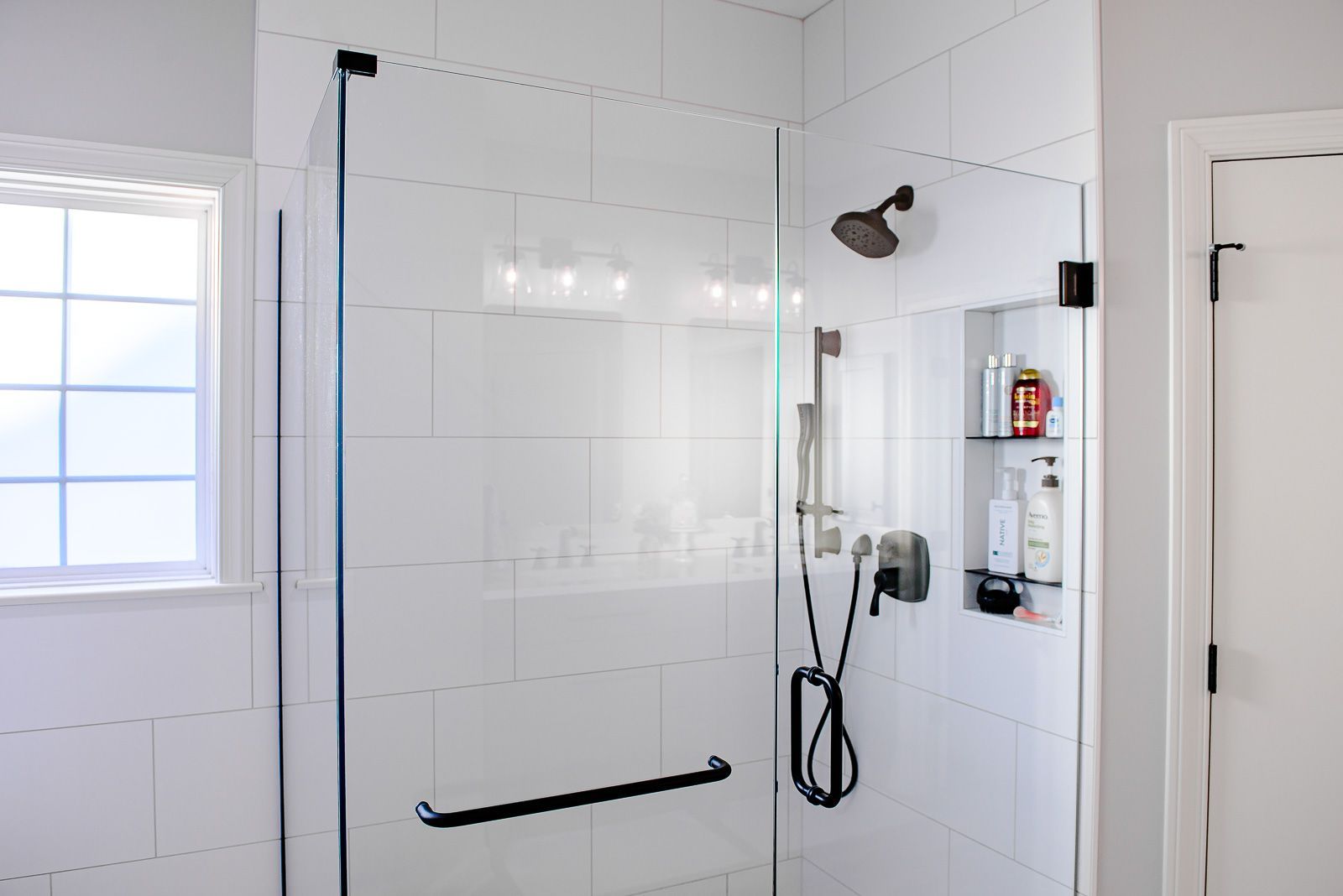 A bathroom with a walk in shower and a window.