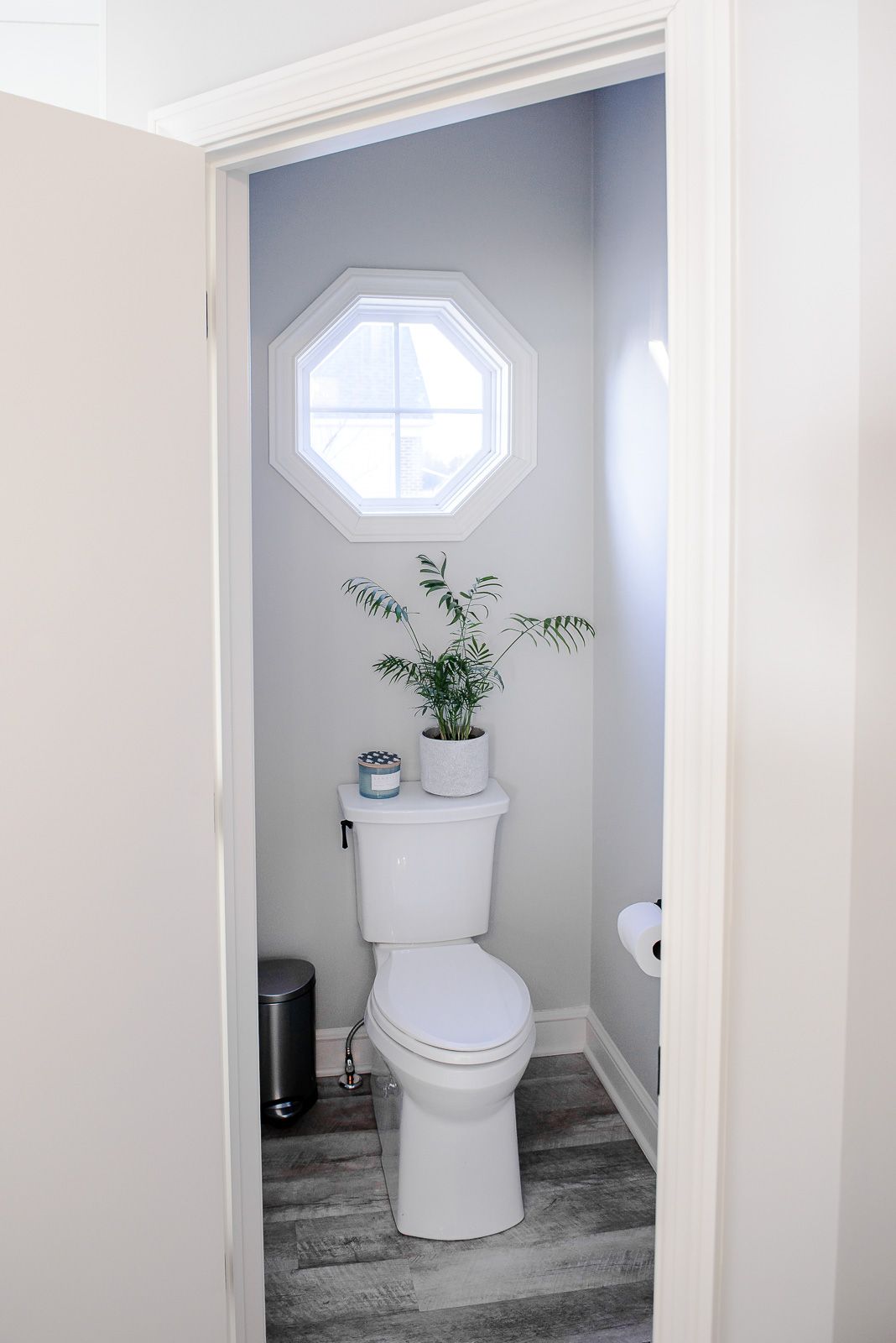 A toilet is sitting in a small bathroom next to a window.
