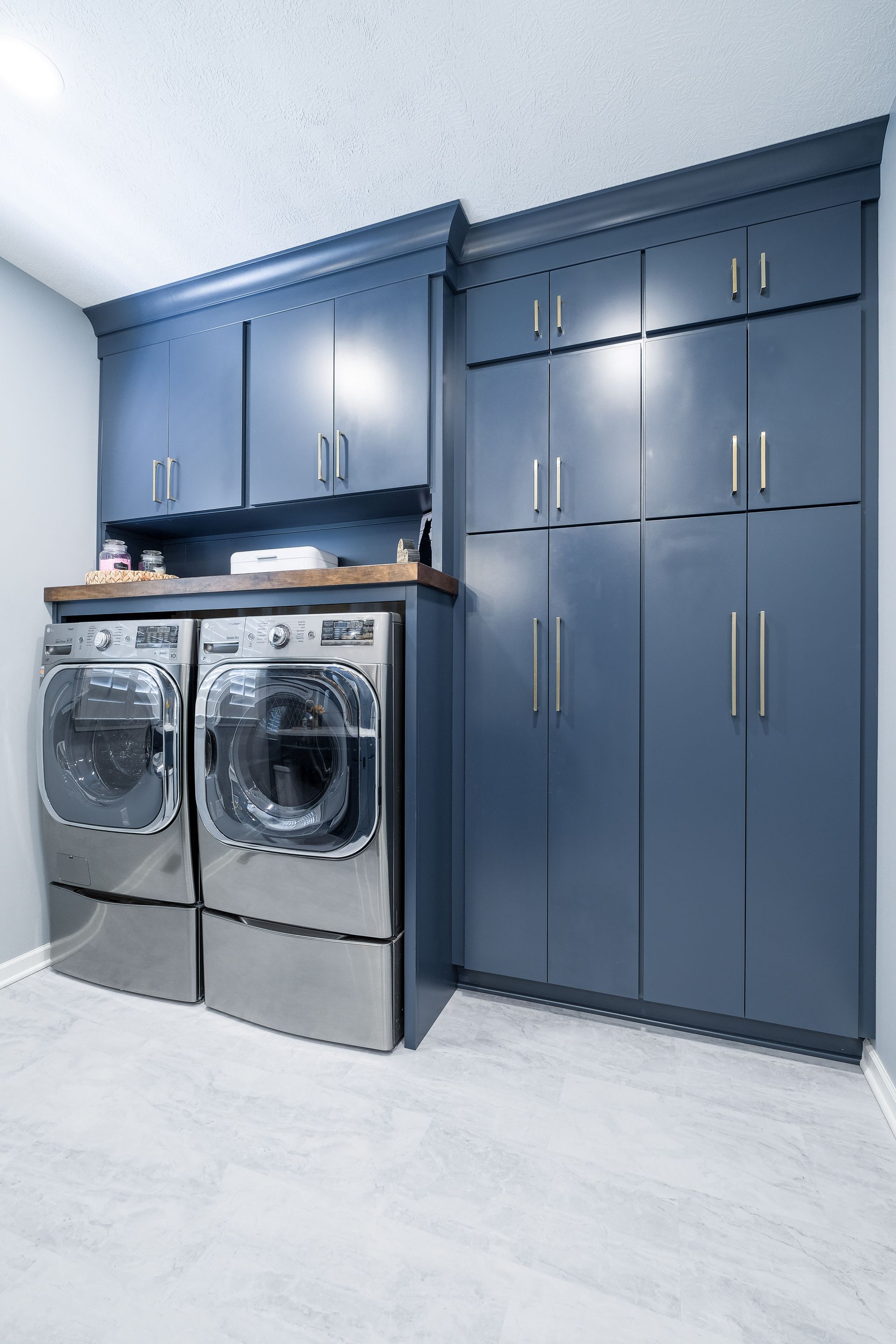 A laundry room with a washer and dryer and blue cabinets.