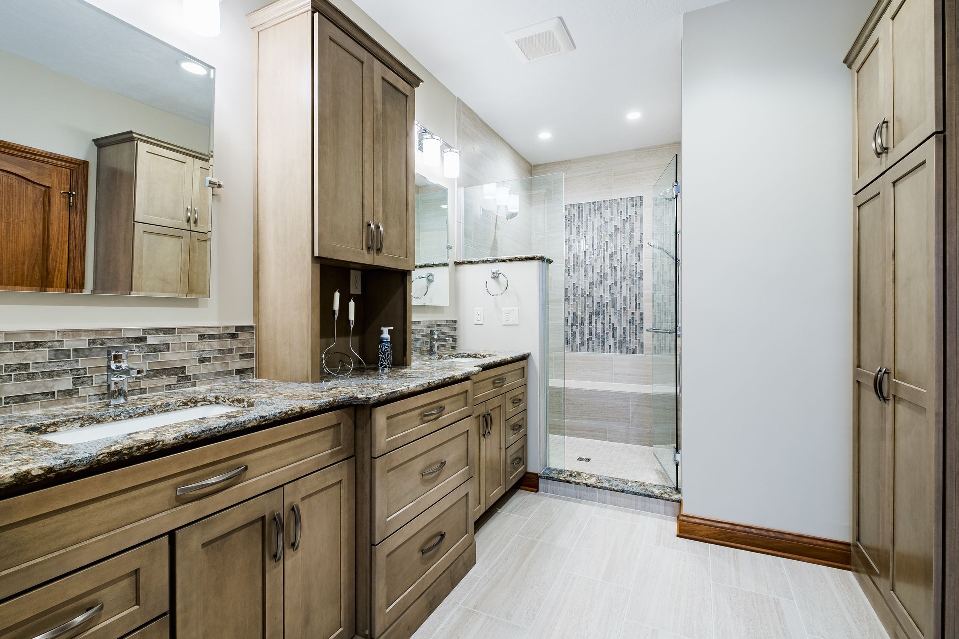 A bathroom with two sinks and a walk in shower.