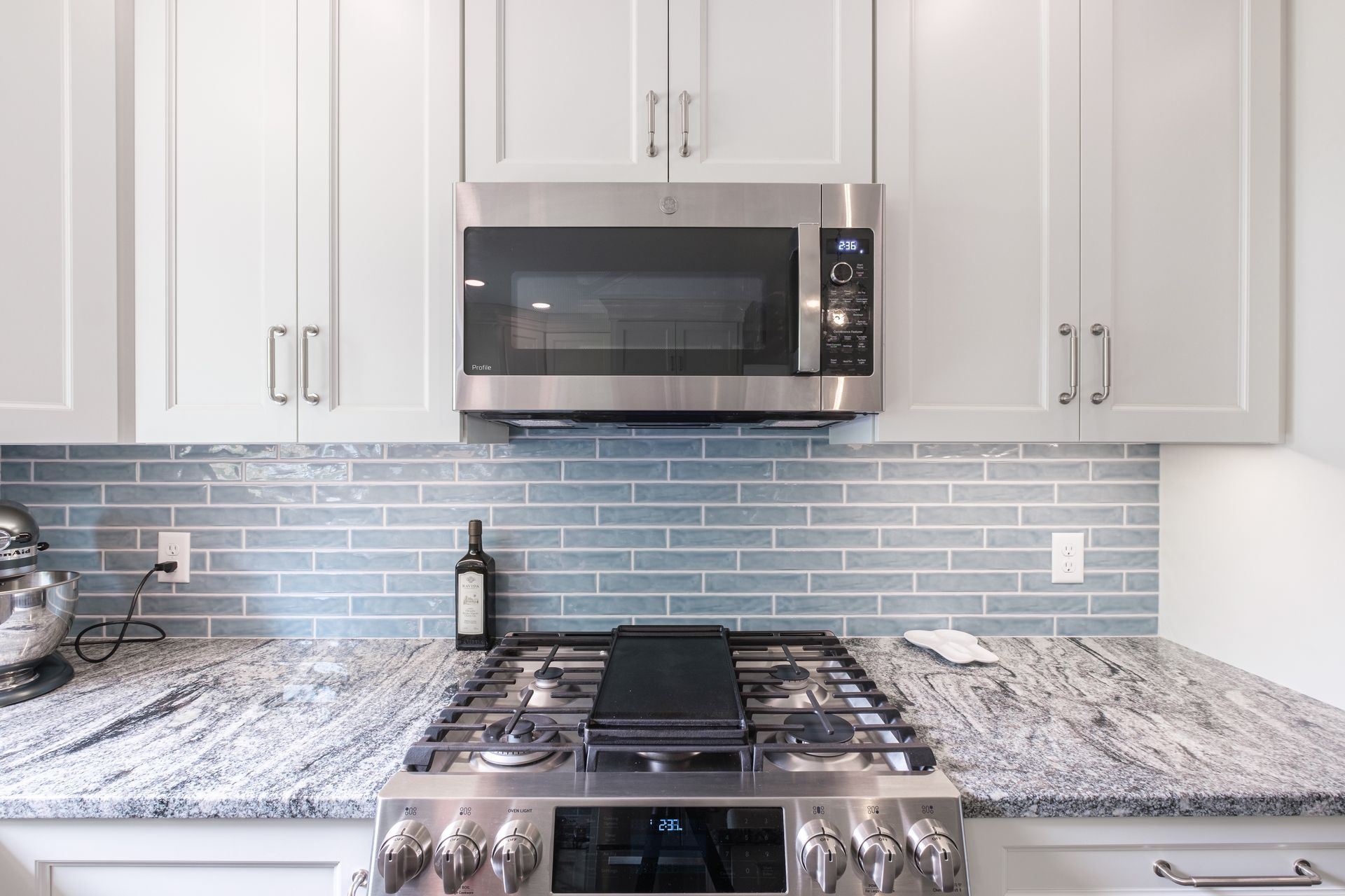 Kitchen with stove, microwave, light gray cabinets, and granite countertops.