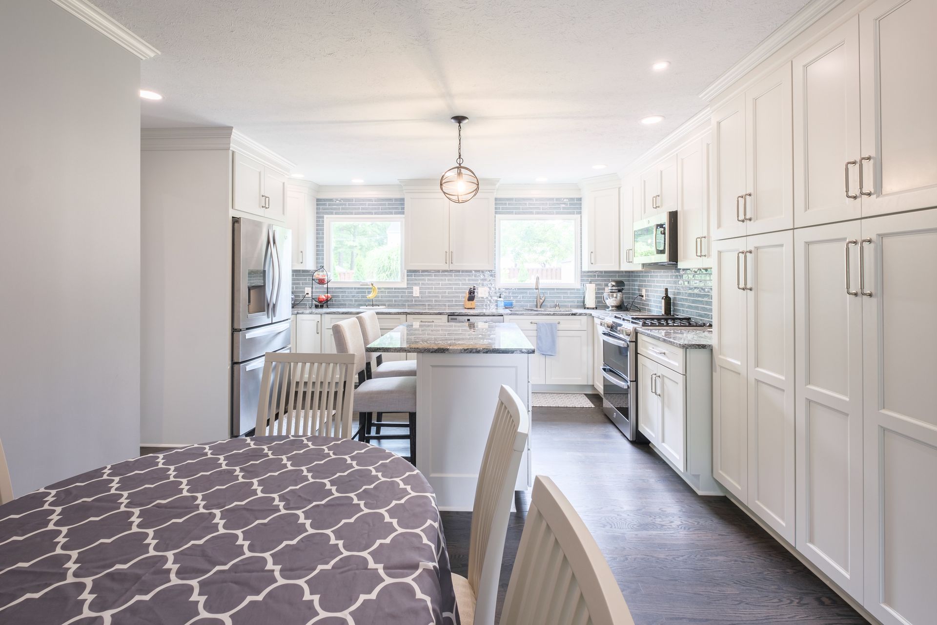 White kitchen with a table in the foreground. Cabinets, island, and appliances.