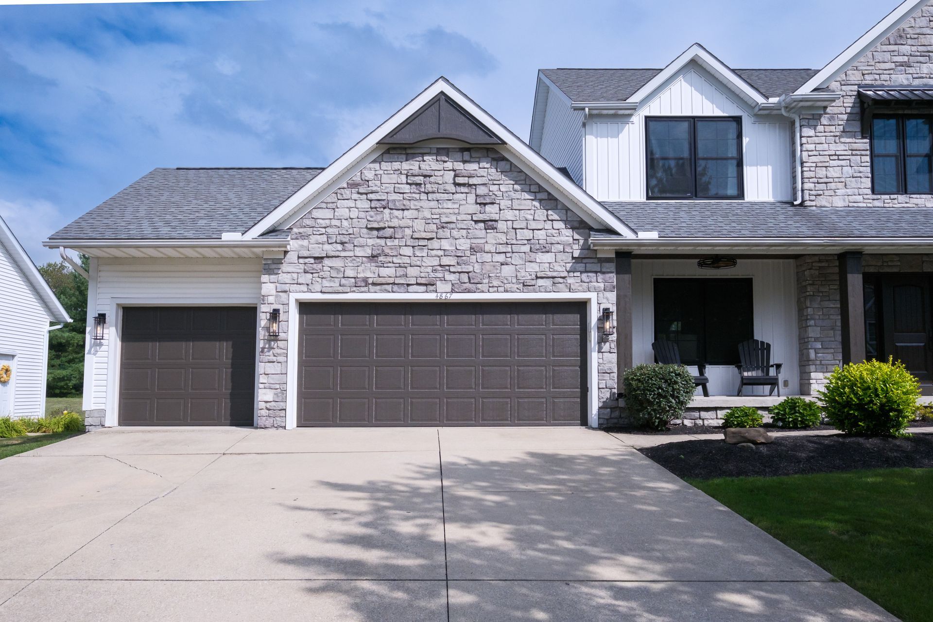 Two-car garage with stone facade and dark brown doors; driveway in front.