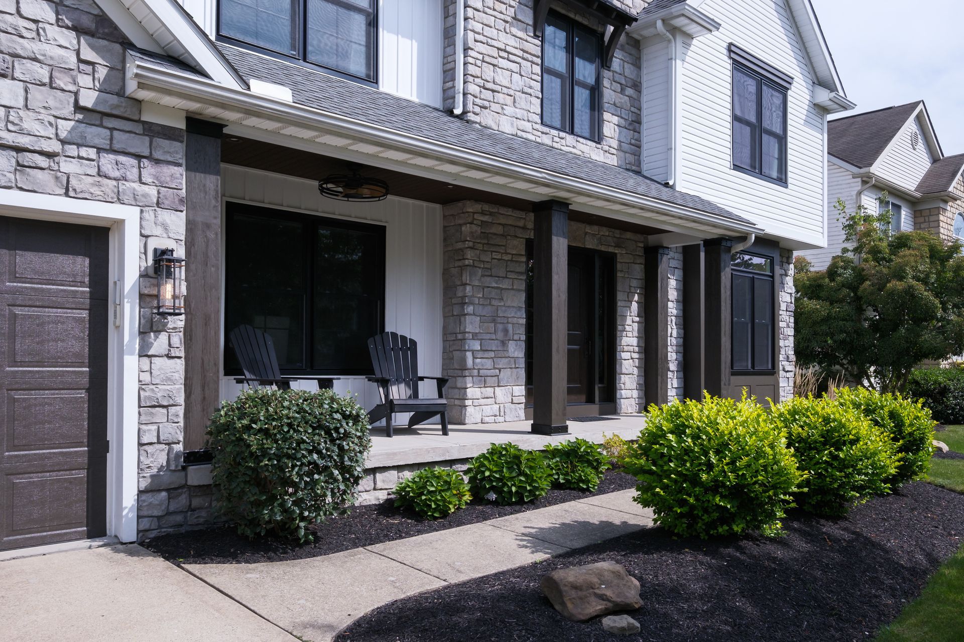 House exterior with stone and white siding, front porch, and landscaping.