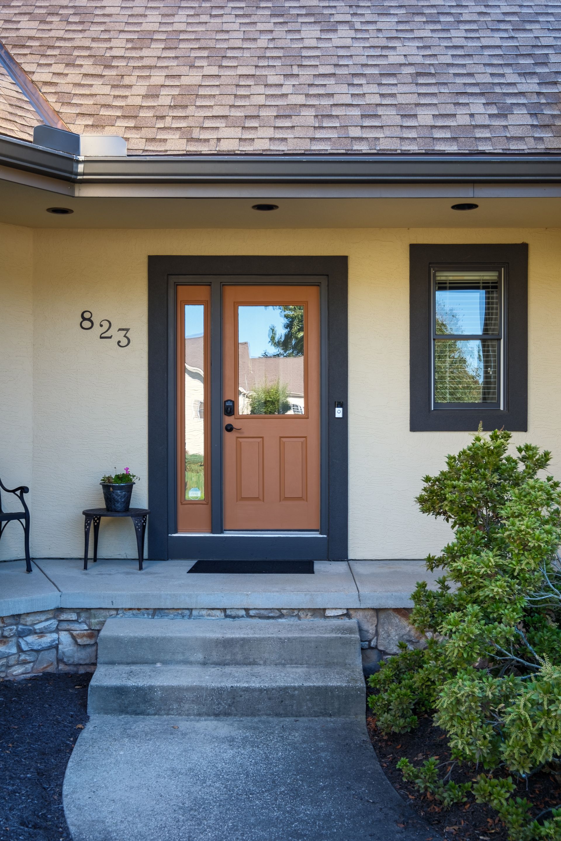 Beige house exterior with brown door, dark gray trim, and steps. Address