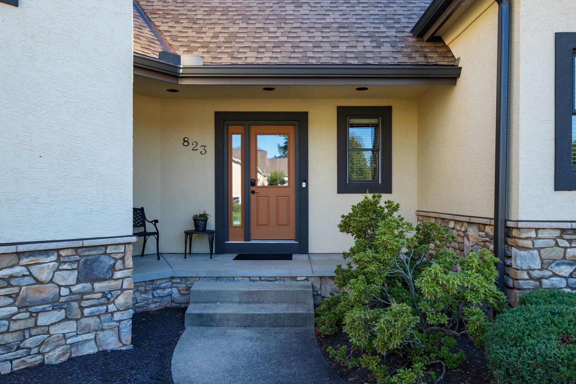 Tan stucco home entrance with a brown door, dark trim, and a small step.