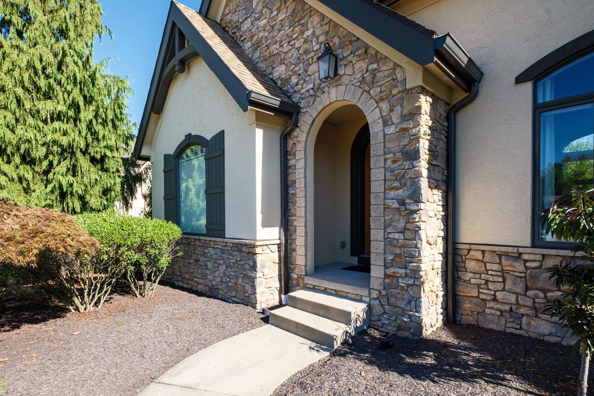 Stone facade entrance with arched doorway, two steps, and a decorative window.