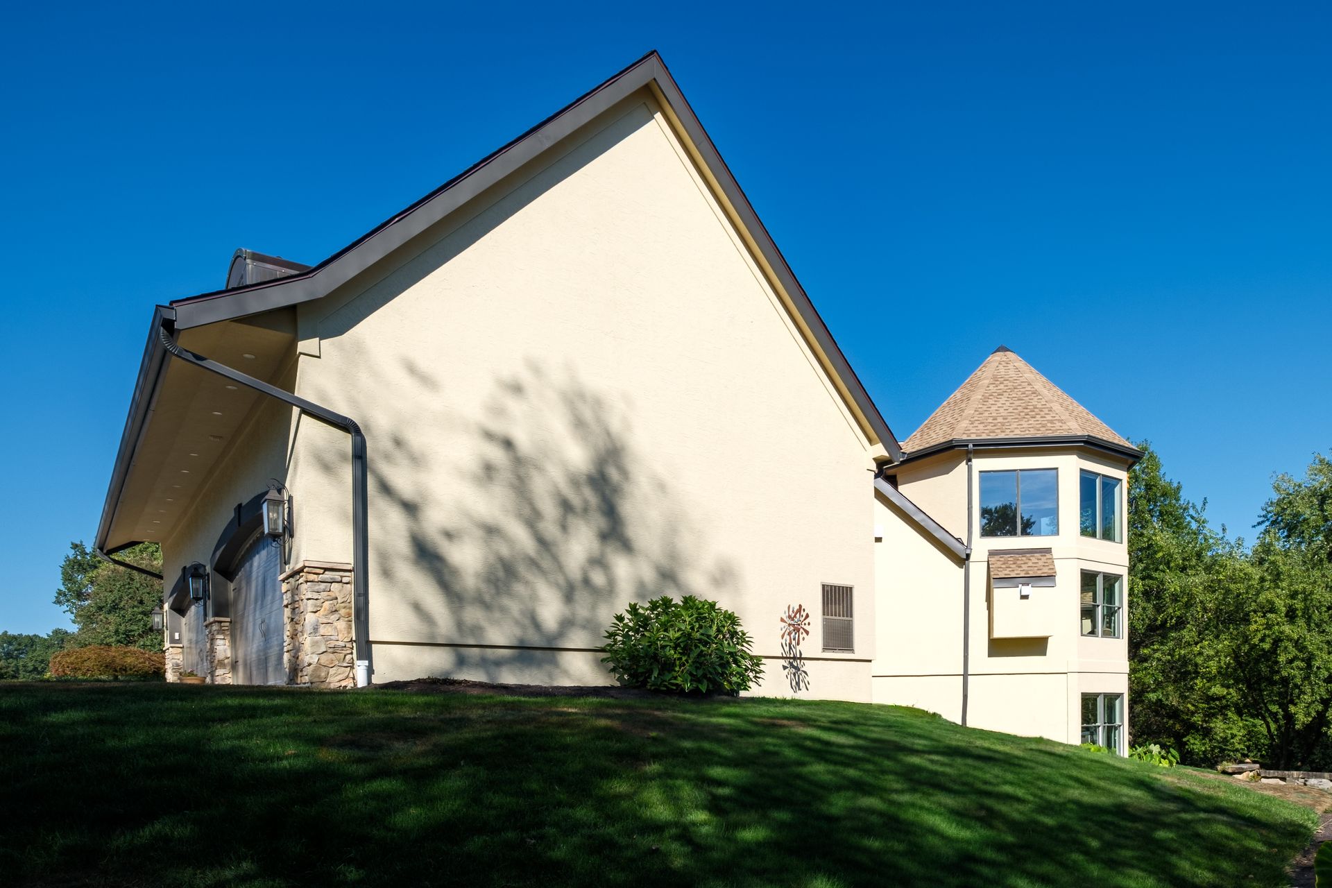 Beige building with a turret on a grassy hill under a blue sky.