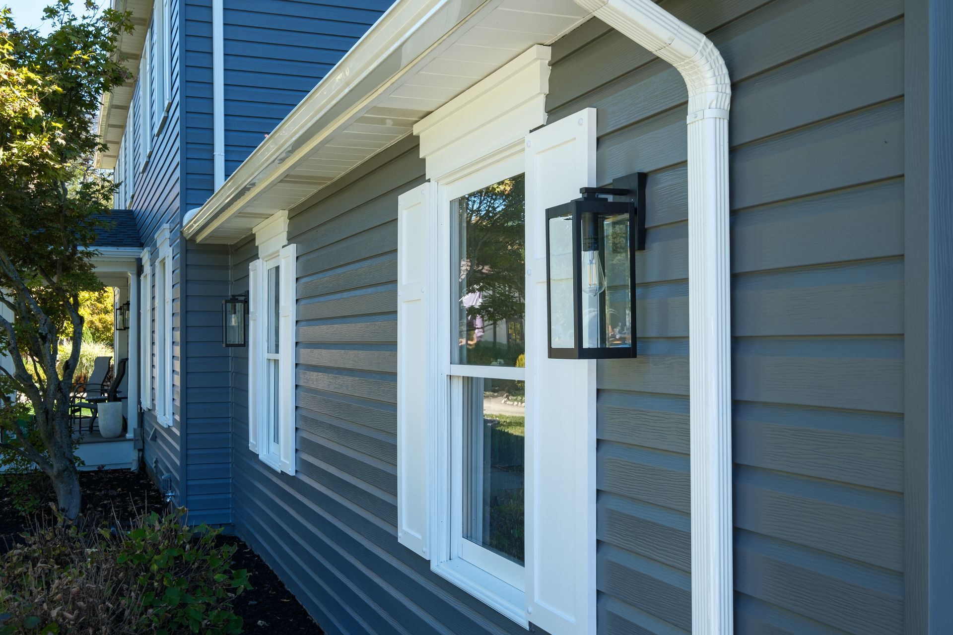 Blue house with white trim, shutters, and outdoor light fixture.
