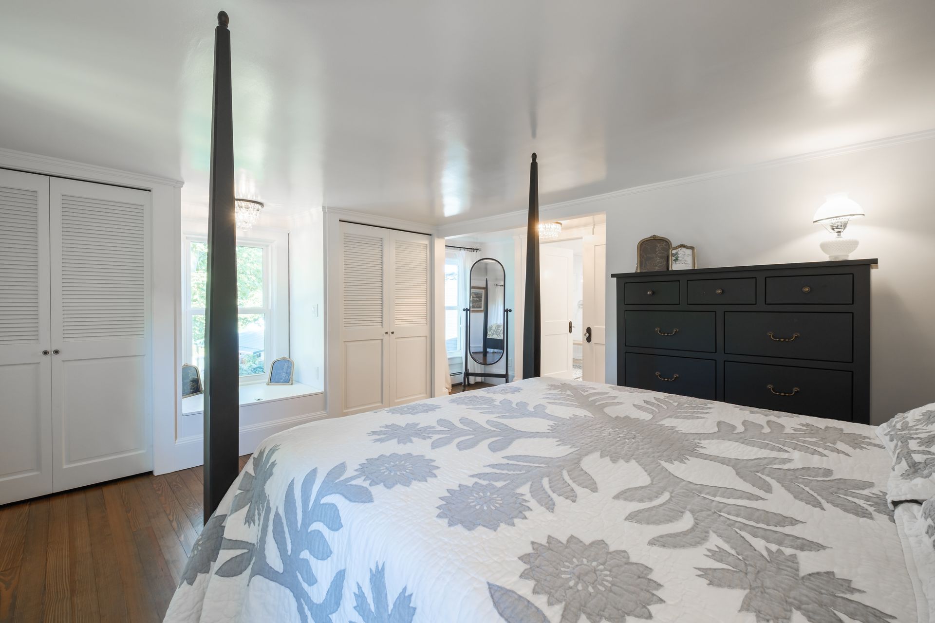 Bedroom with a bed, dresser, and large closet doors; white and grey color scheme.