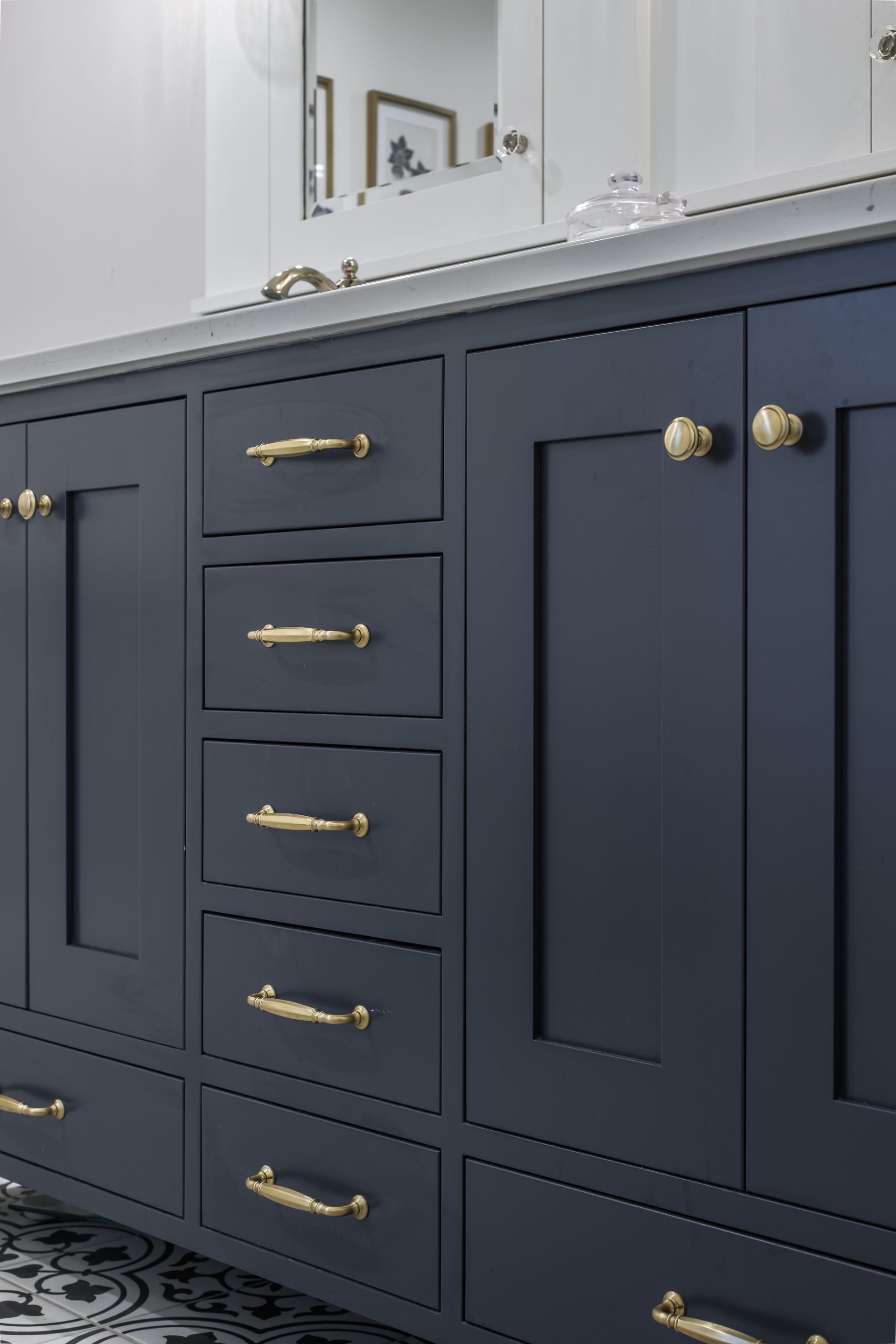 Dark blue bathroom vanity with gold hardware and white countertop.