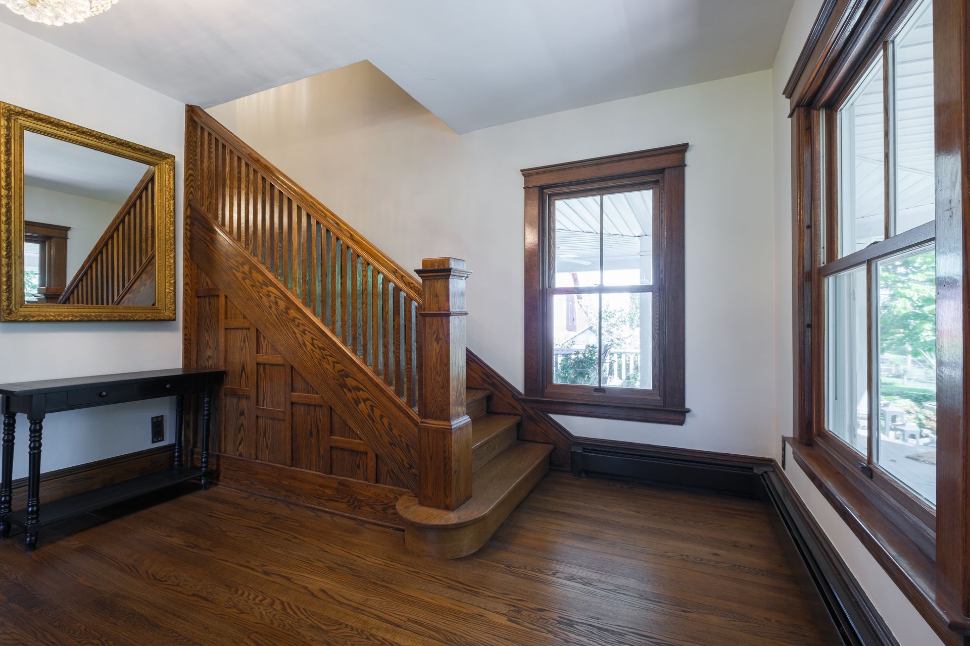 Wooden staircase in a home with wood floors, a mirror, and a window.
