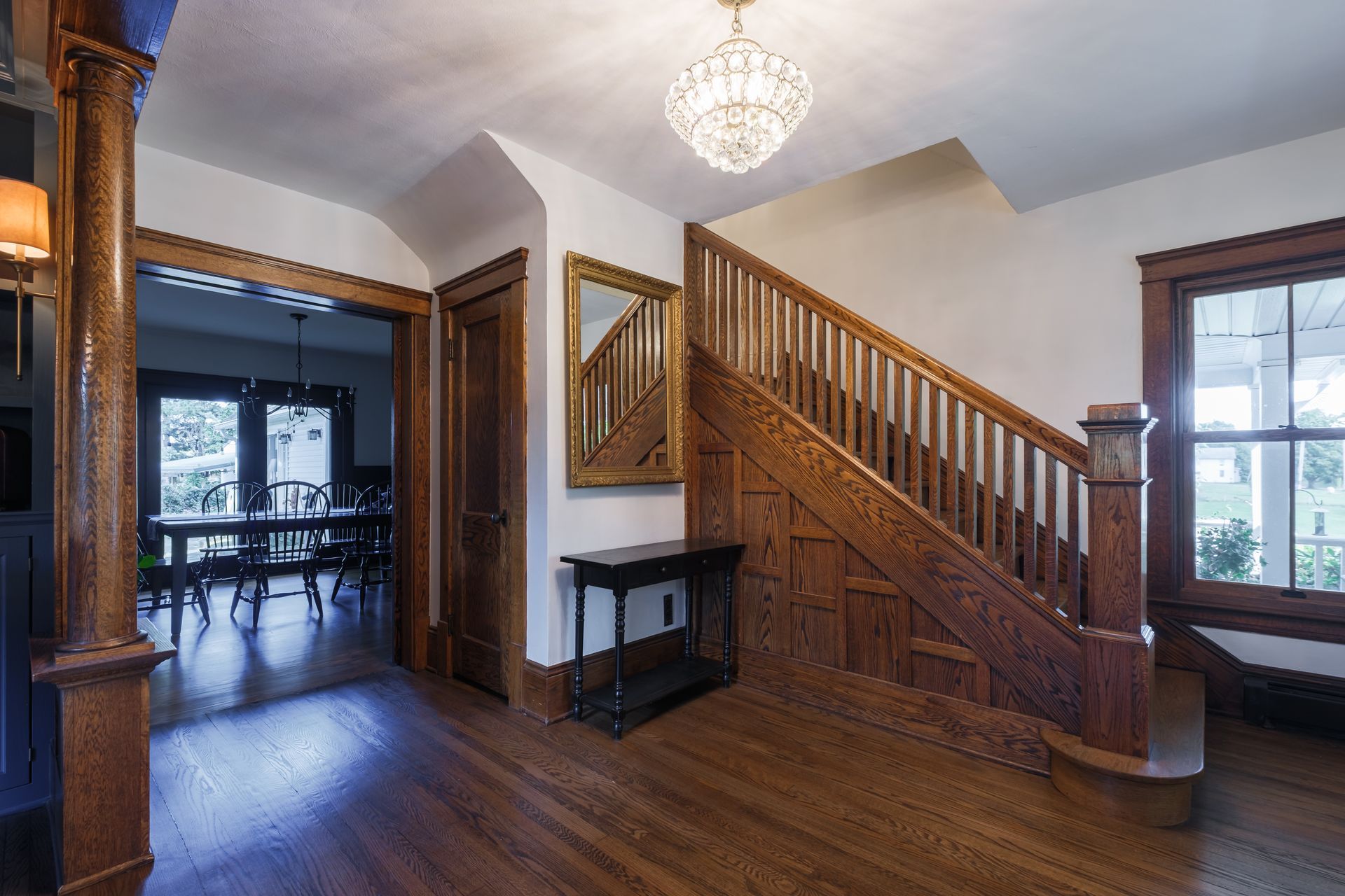 Interior hallway with wooden staircase, wood floors, and a crystal chandelier.