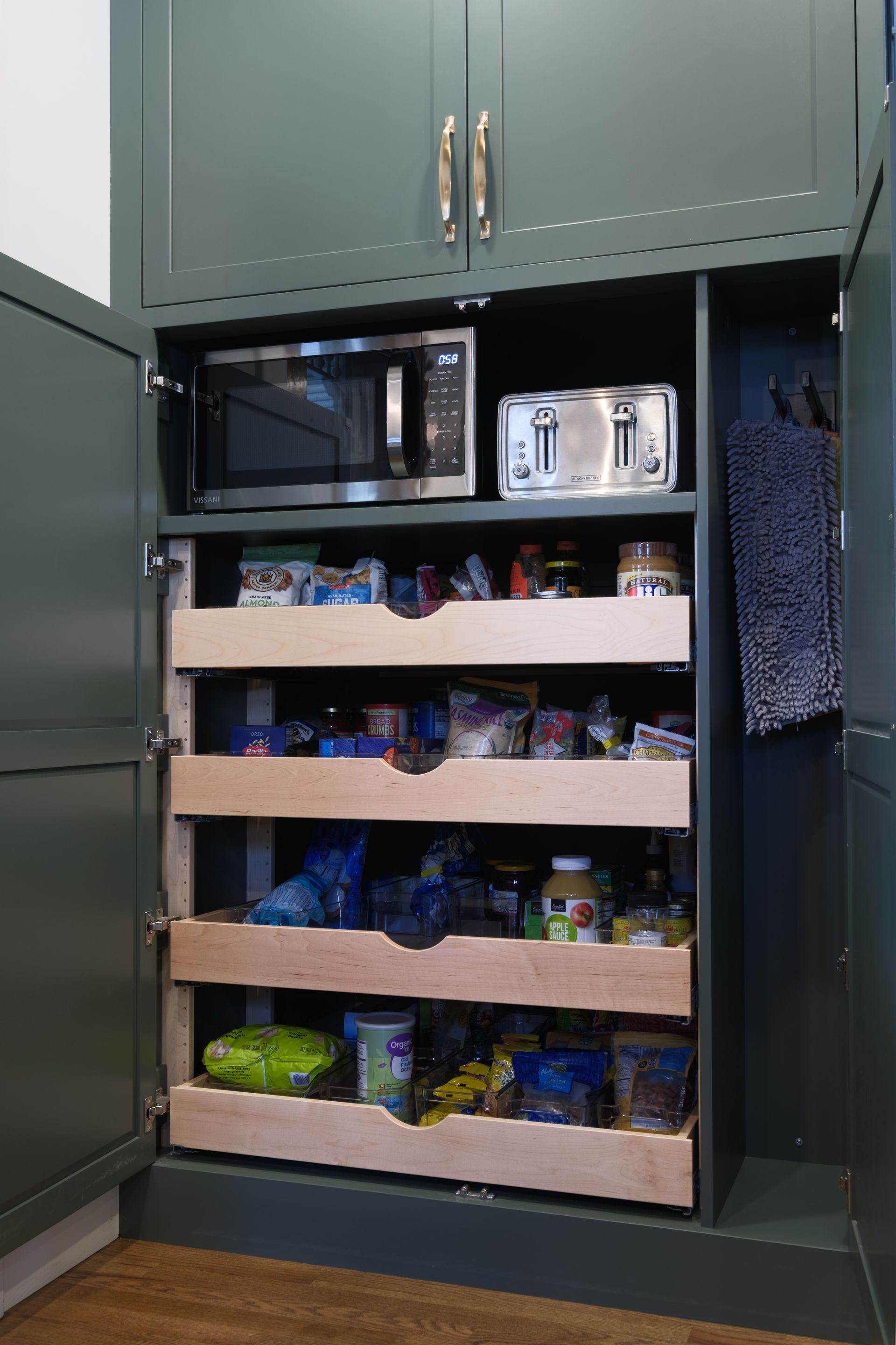 Green pantry cabinet with pull-out drawers, microwave, and toaster.
