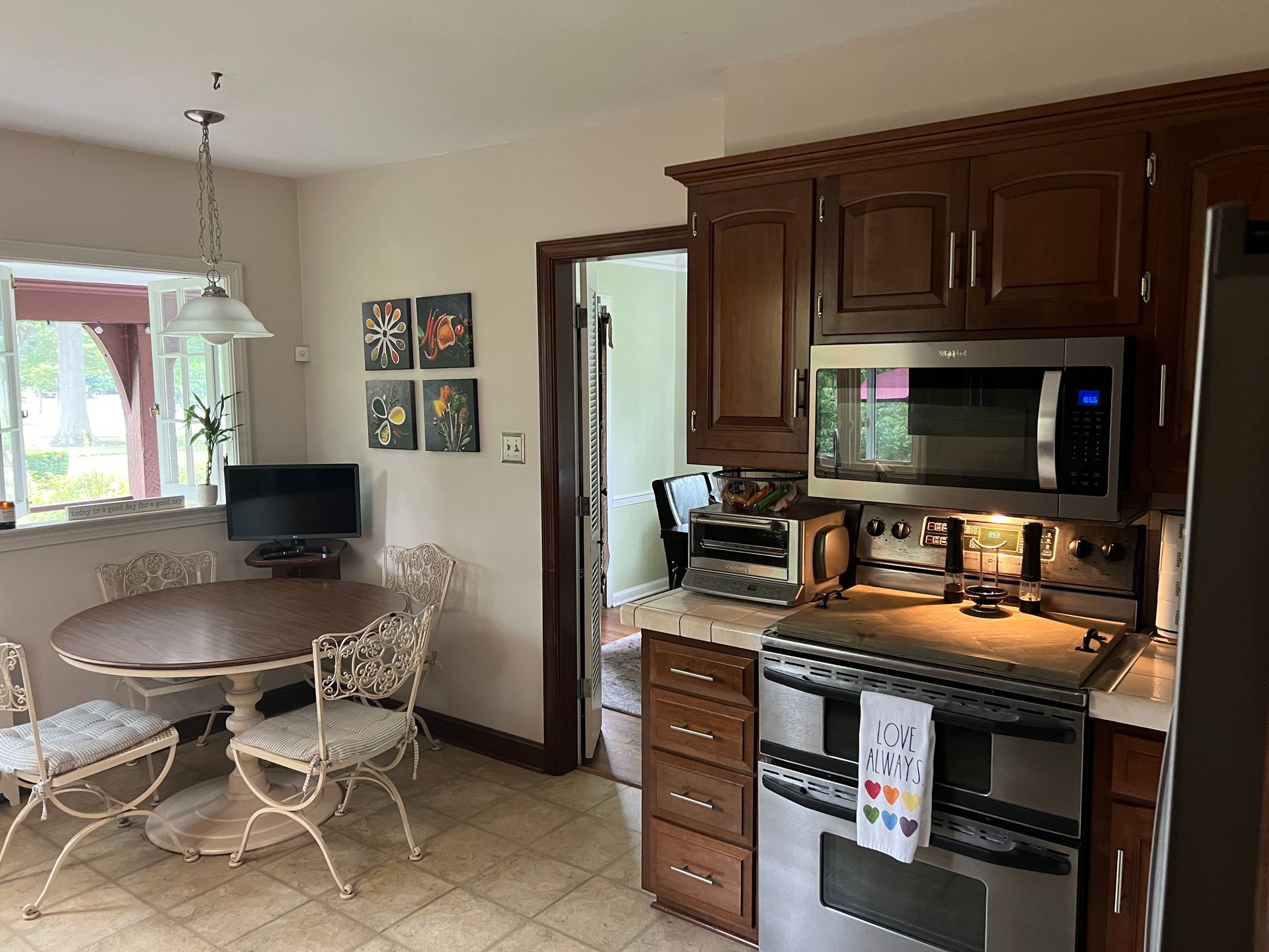 A kitchen with a table , chairs , stove , microwave and refrigerator.