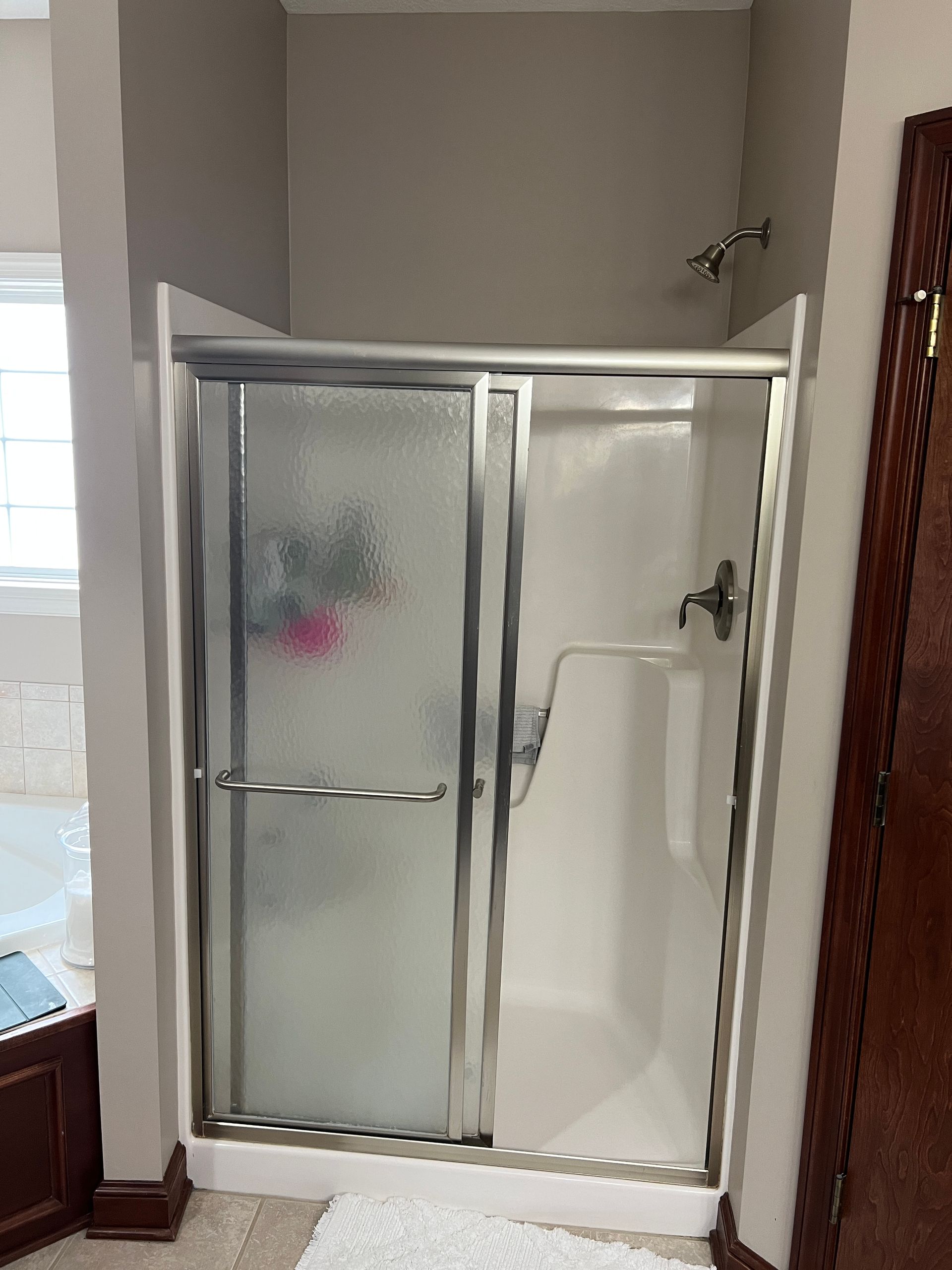 A bathroom with a sliding glass shower door and a tub.