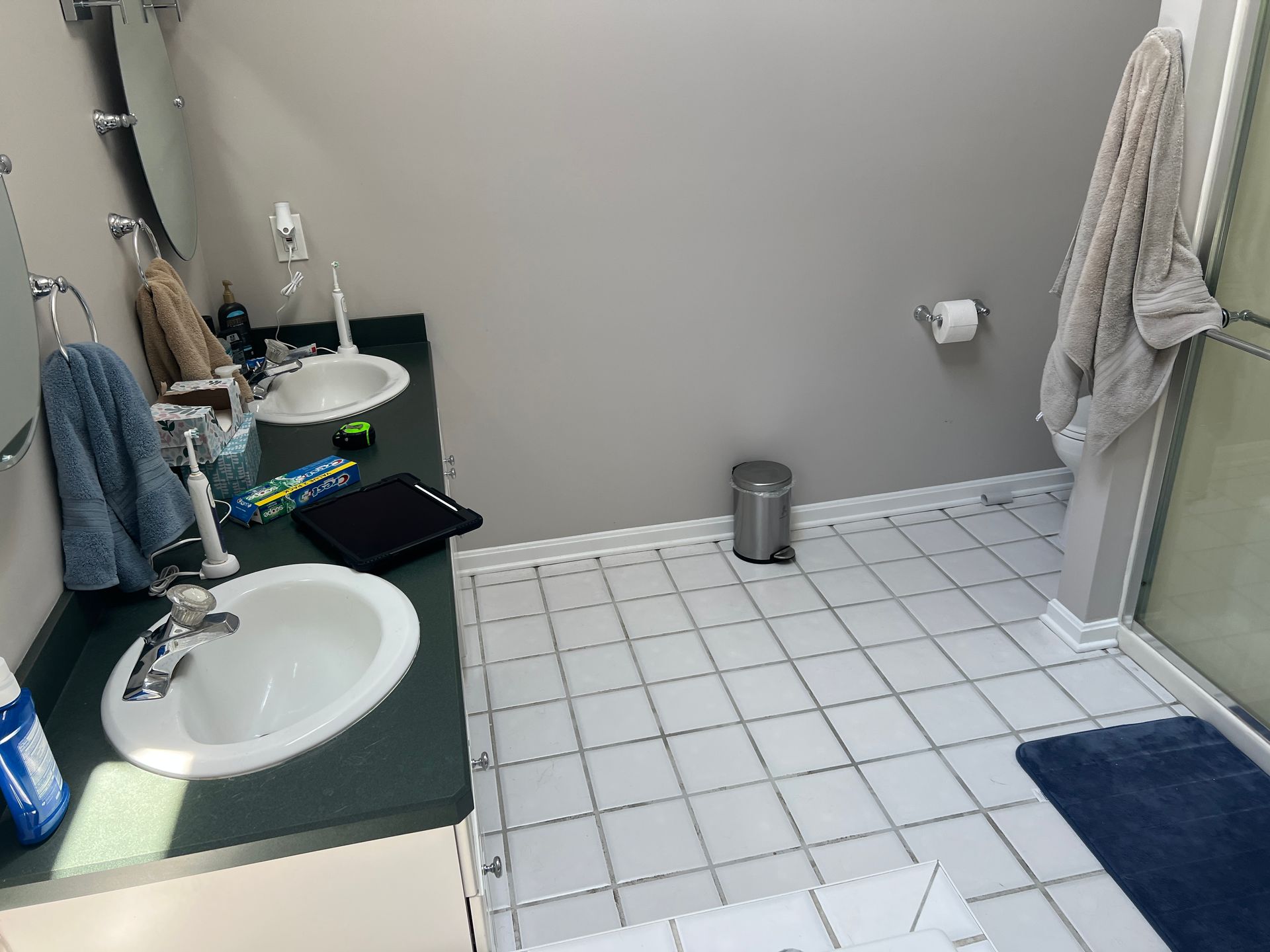 A bathroom with two sinks and a trash can