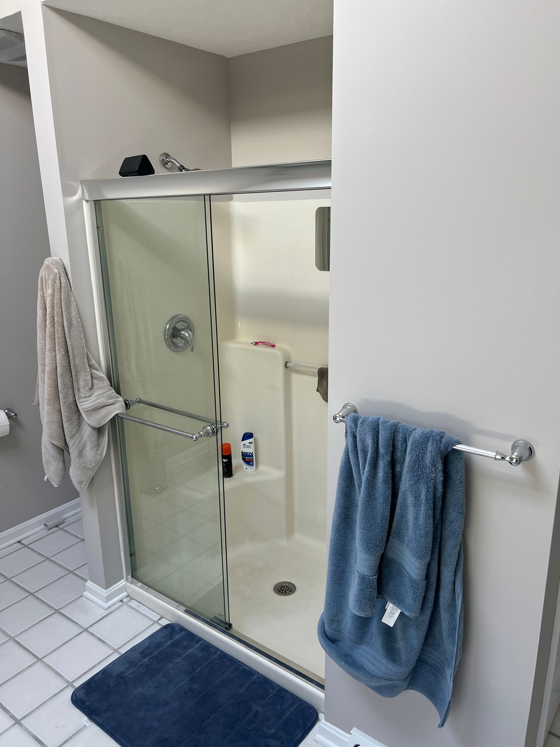 A bathroom with a shower and a blue towel on the wall
